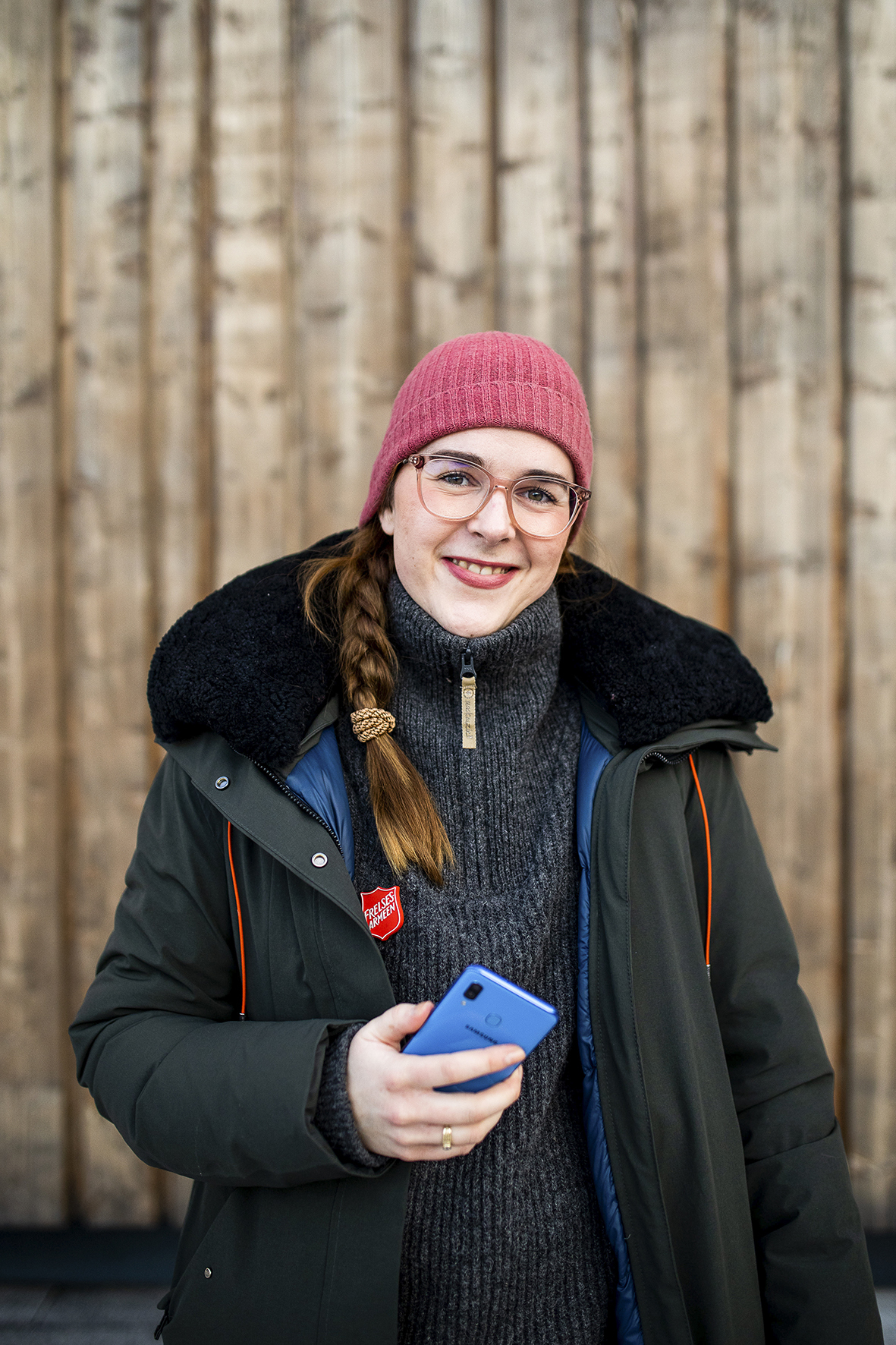 Liza som smiler og holder en mobiltelefon i hånda.