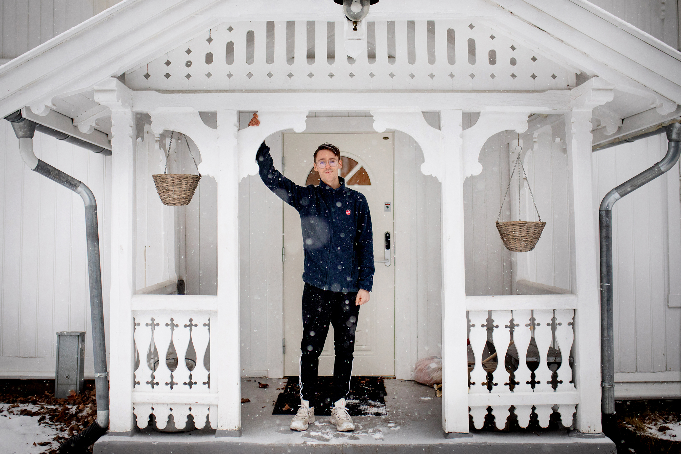 Ung mann står ved det hvite inngangspartiet i tre, til Frelsesarmeen, Groruddalen, Stig Gård.