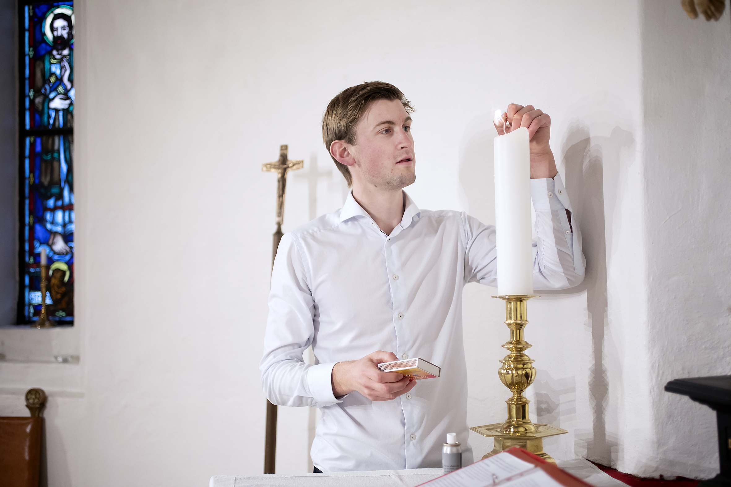 Thor er nå i full gang som prest i Salhus kirke. Her tenner han alterlysene.