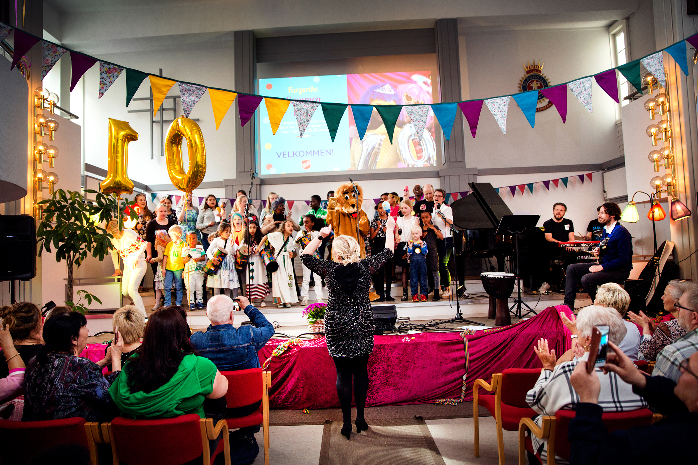Det første bildet viser Tone Berg som står bak disken i kafeen på Sammen. På det andre bildet står hun med ryggen til og dirigerer koret Closer.