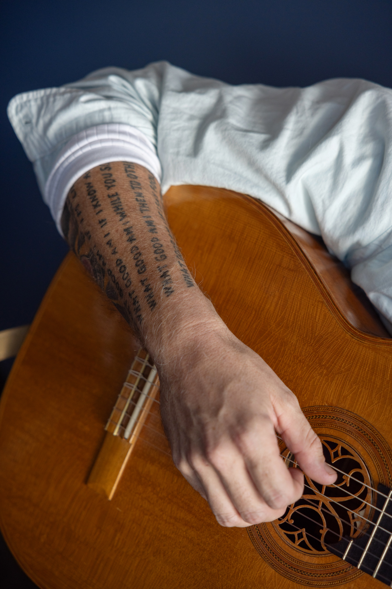 Foto: Nærbilde av hånd med tatoveringer som spiller gitar.