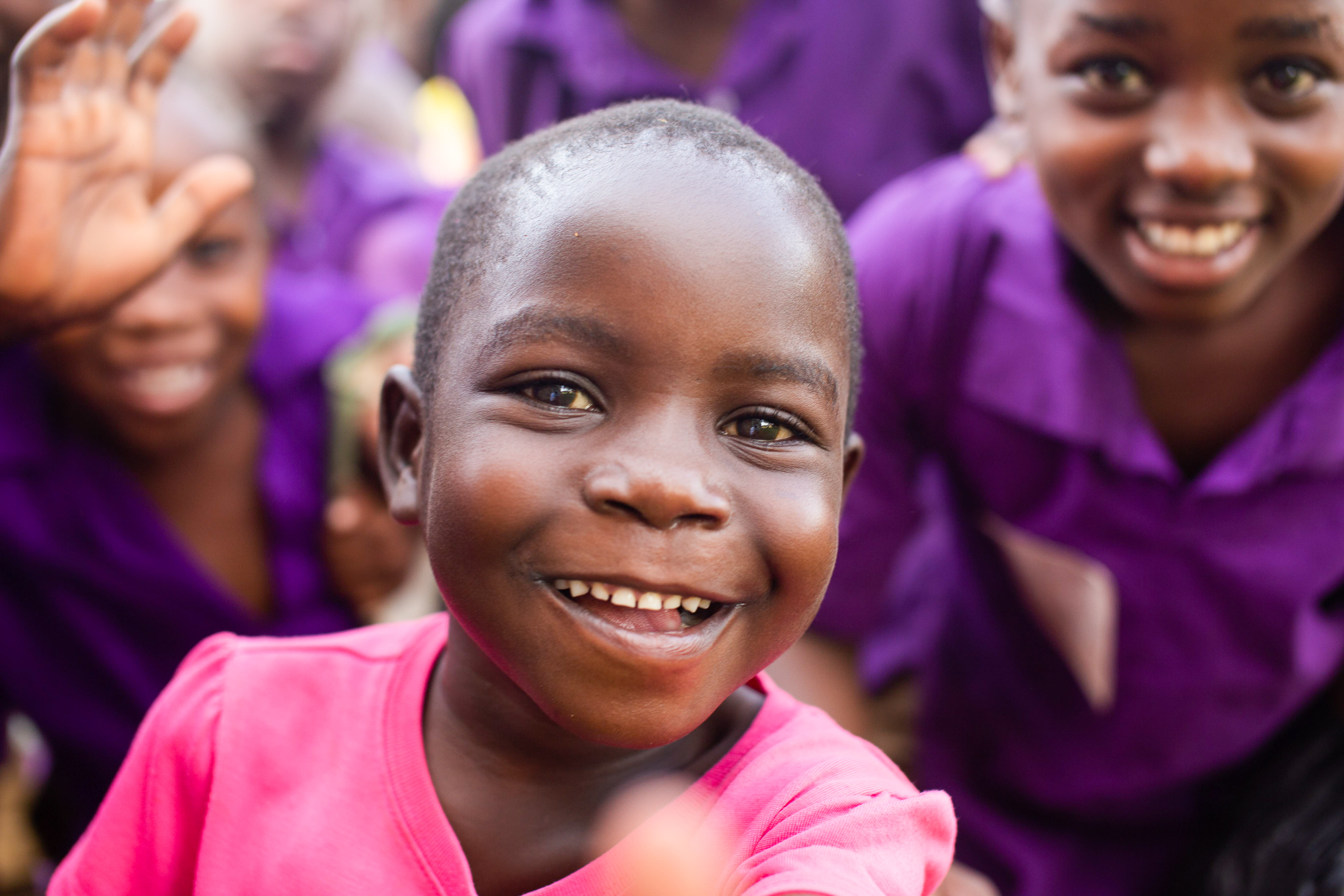 En smilende liten jente i rosa kjole