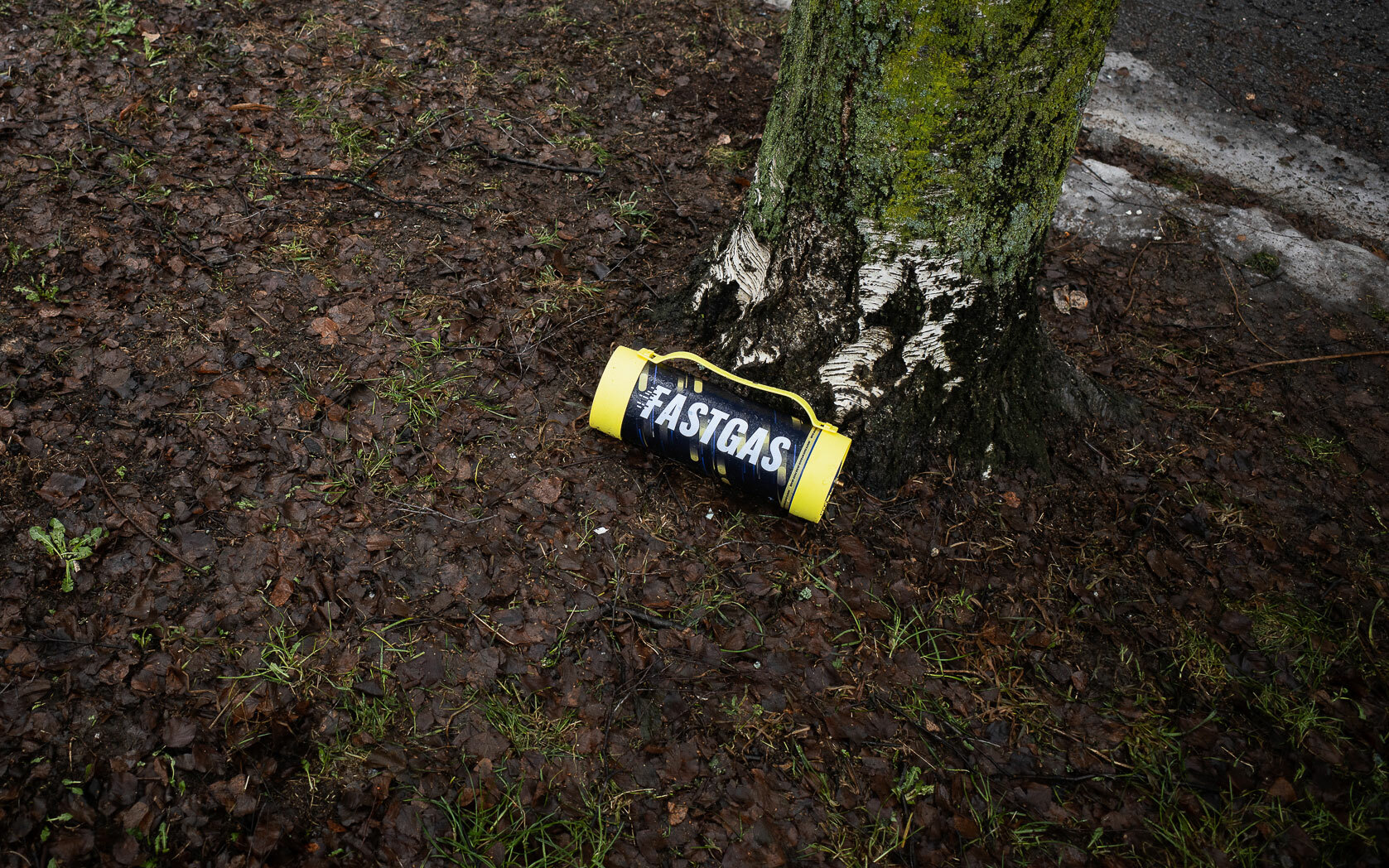Tom boks med påskriften "fastgas" ligger slengt på bakken, under et tre.
