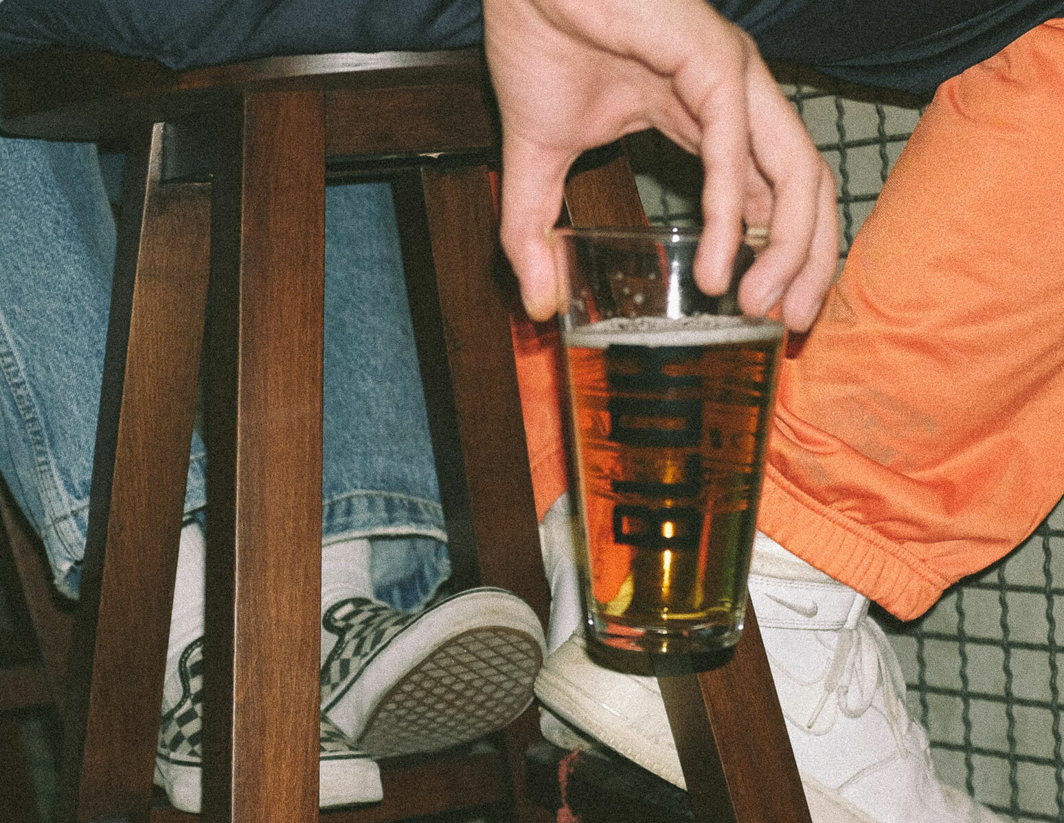 Glass med pils. En hånd som holder det. Sitter på barkrakk.