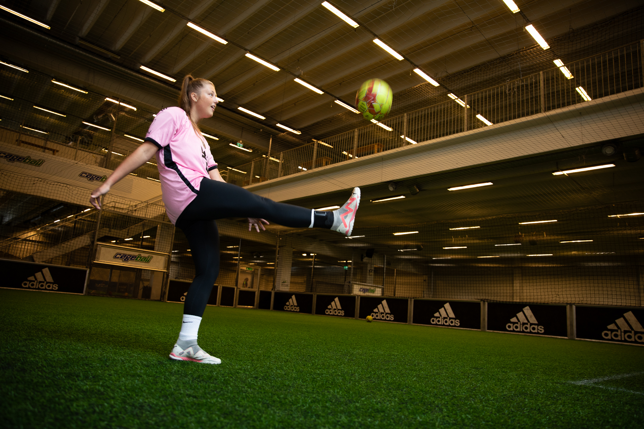 Foto: En kvinne i rosa t-skjorte og svarte treningsbukser trikser med ball.