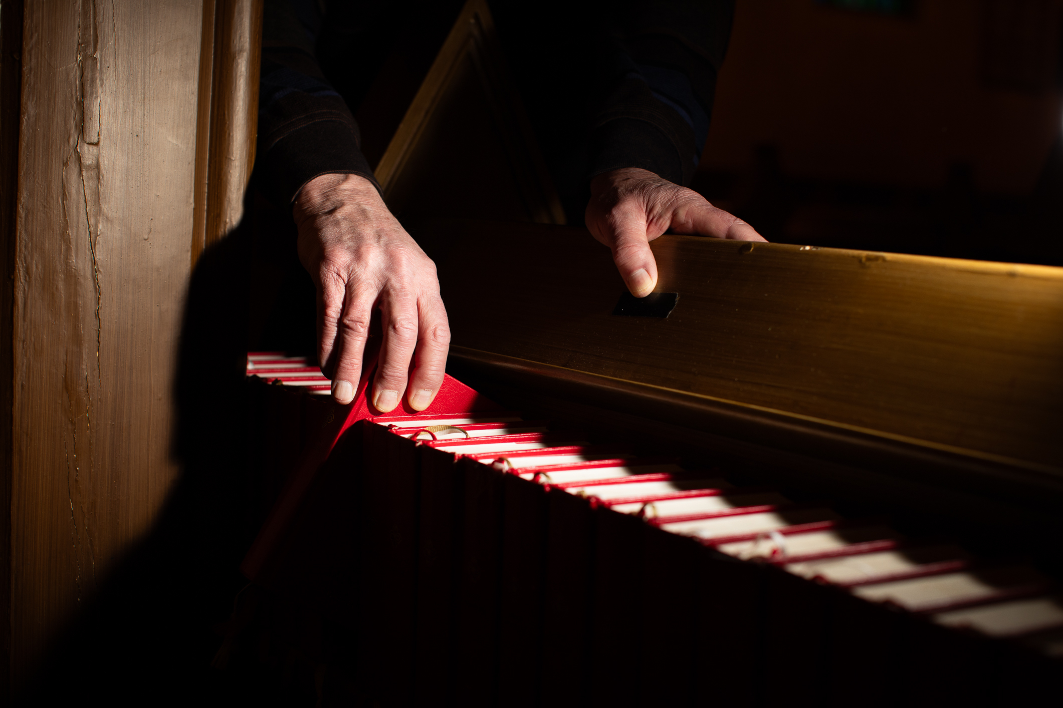 To bilder ved siden av hverandre som først viser en hånd som tar etter salmebok i en lang rekke og deretter som viser den pene rekken med bøker.