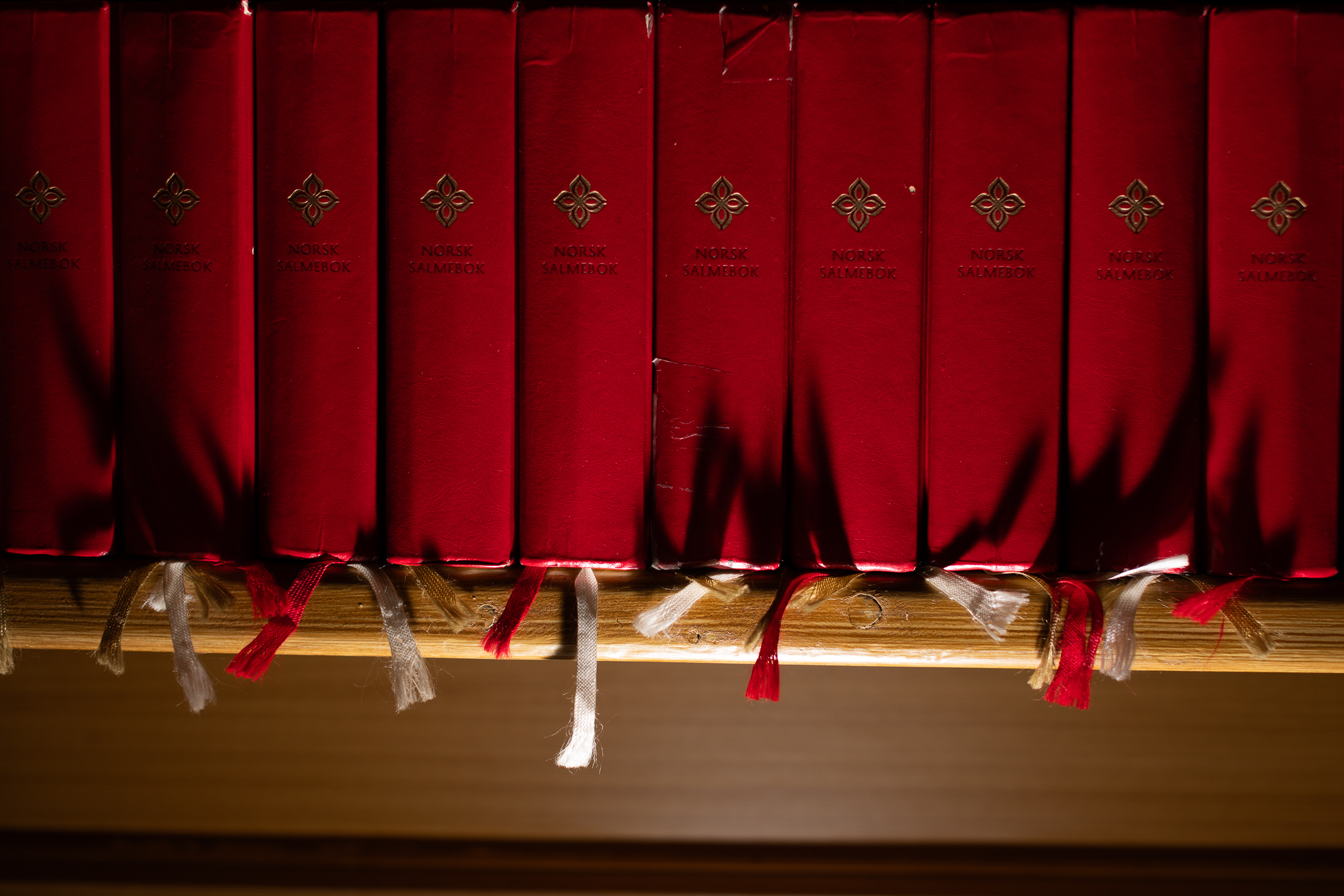 To bilder ved siden av hverandre som først viser en hånd som tar etter salmebok i en lang rekke og deretter som viser den pene rekken med bøker.