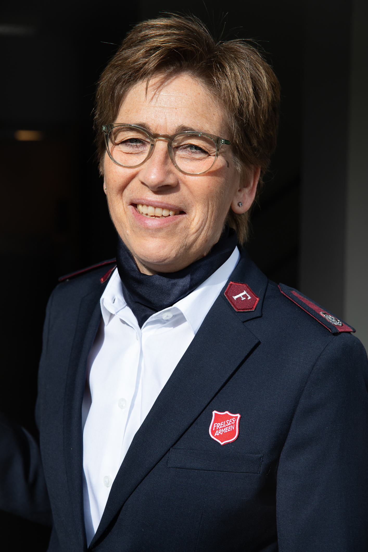 Middelaldrende kvinne  i Frelsesarmeens uniform. Tørkle i halsen, hvit skjorte og blå blaser.