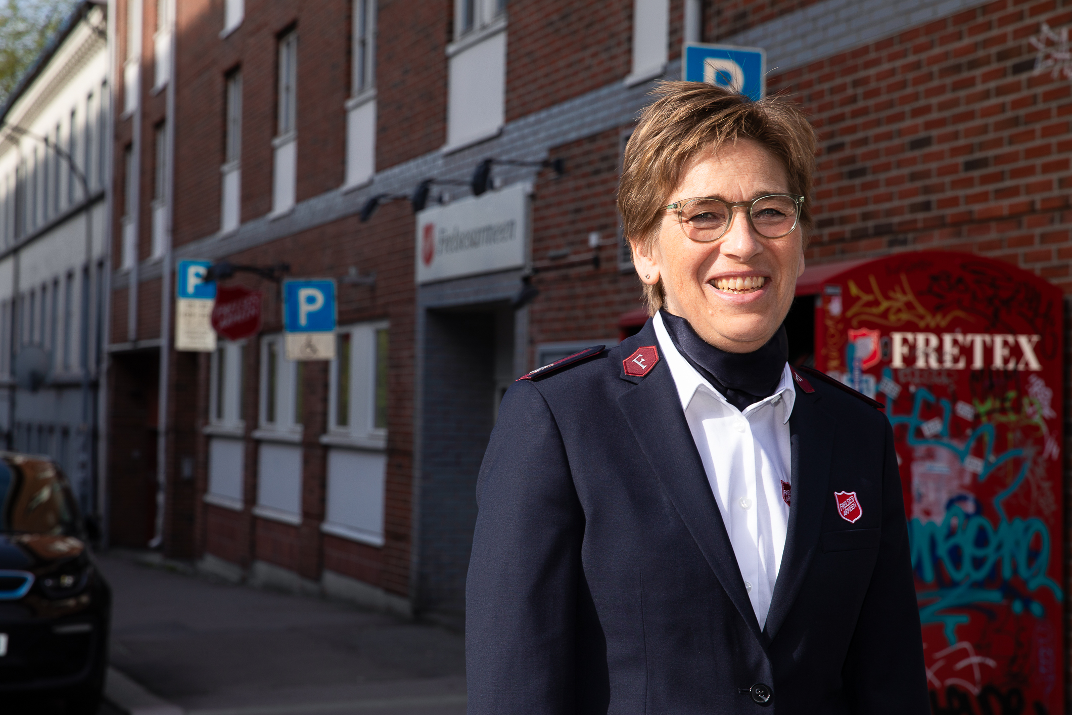 Middelaldrende kvinne  i Frelsesarmeens uniform utenfor Fretex