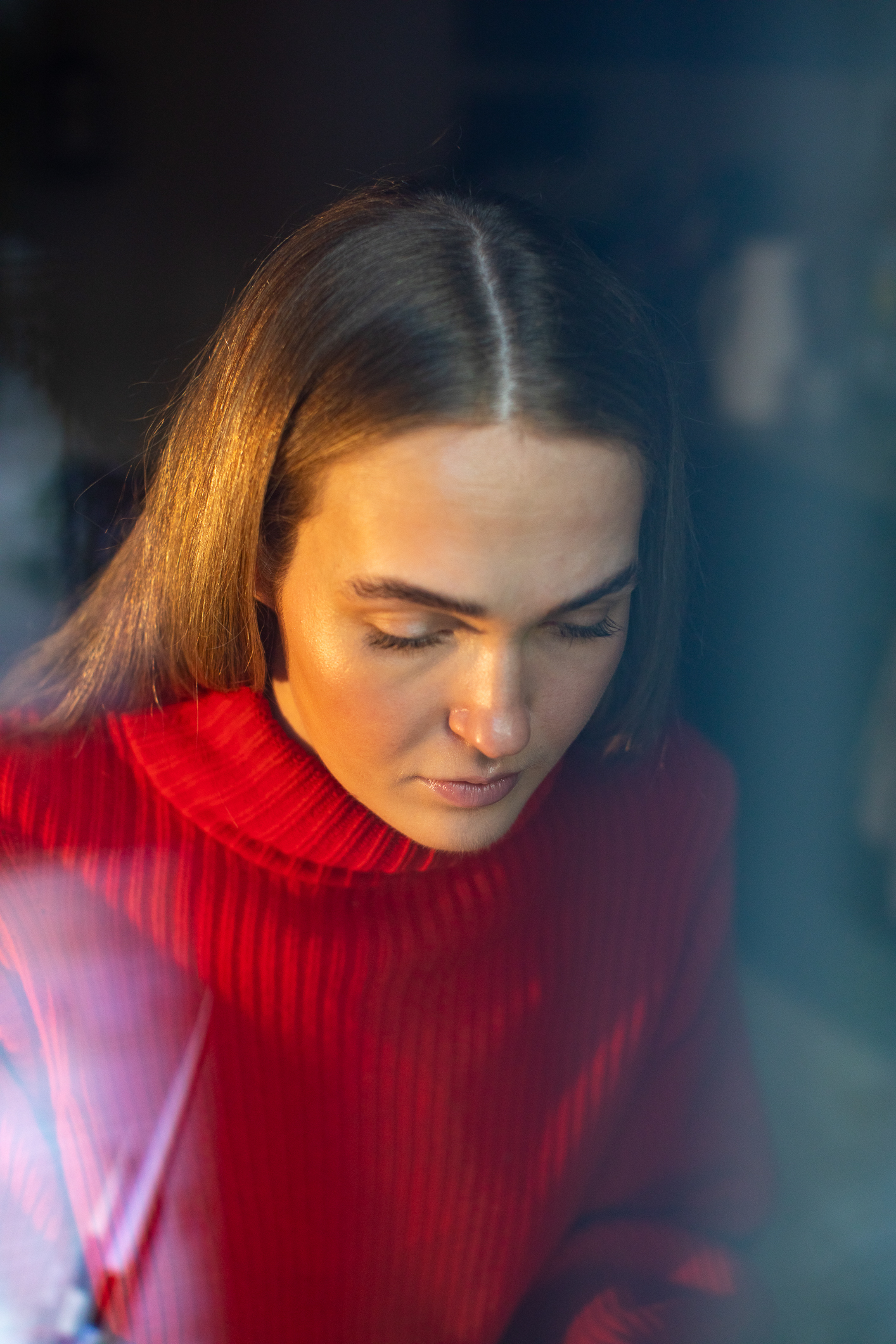 Kvinne med langt hår og julerød genser ser ned.