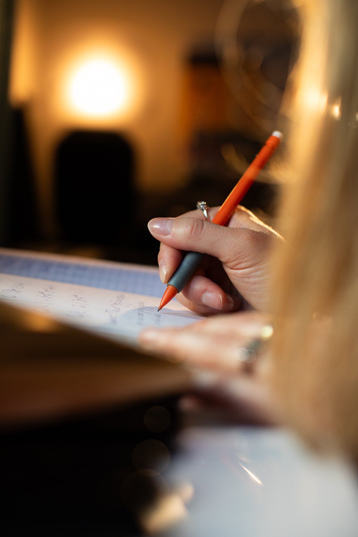 Hånd med rød penn skriver i ei bok.