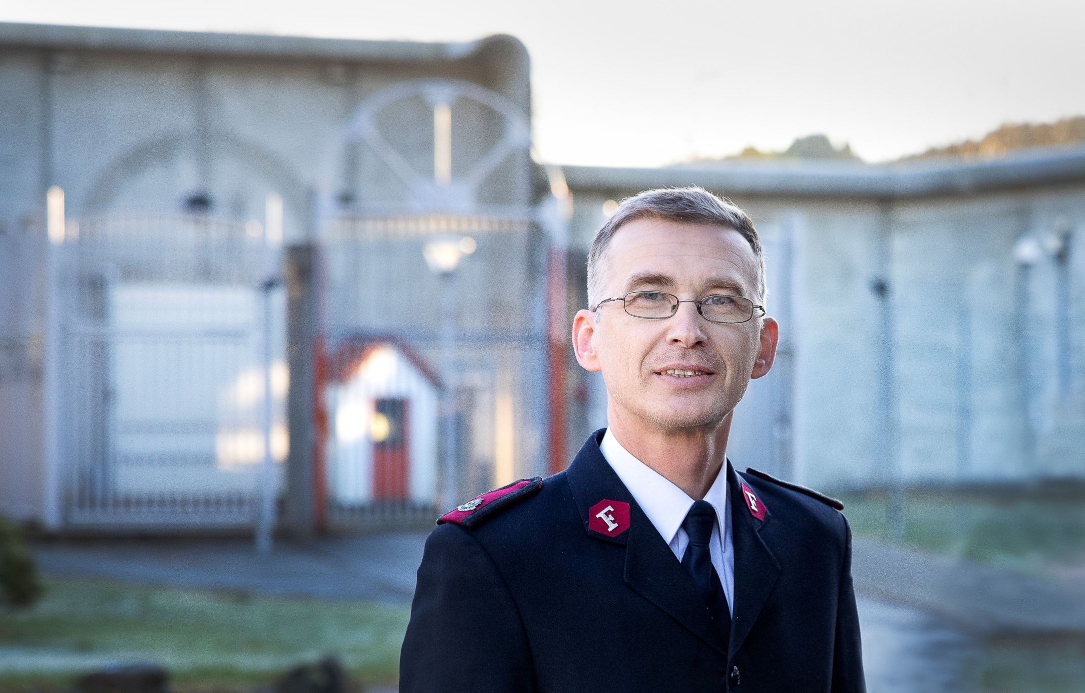 Mann med frelsesarméuniform med fengselsmurer bak
