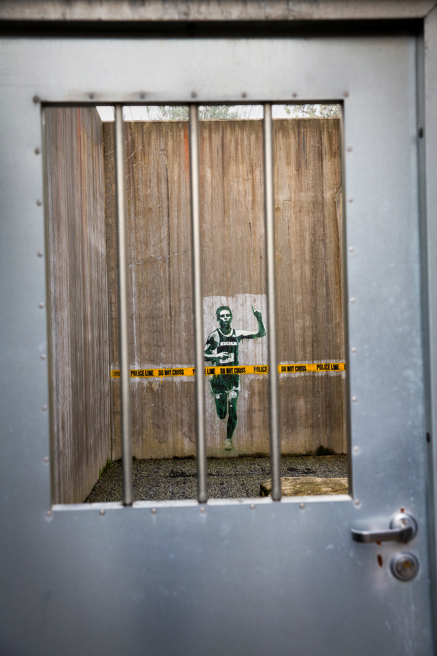 Grafitti på en vegg i luftegården i fengseletsom viser en maratonløper som krysser mållinjen der det står «Do not cross.»