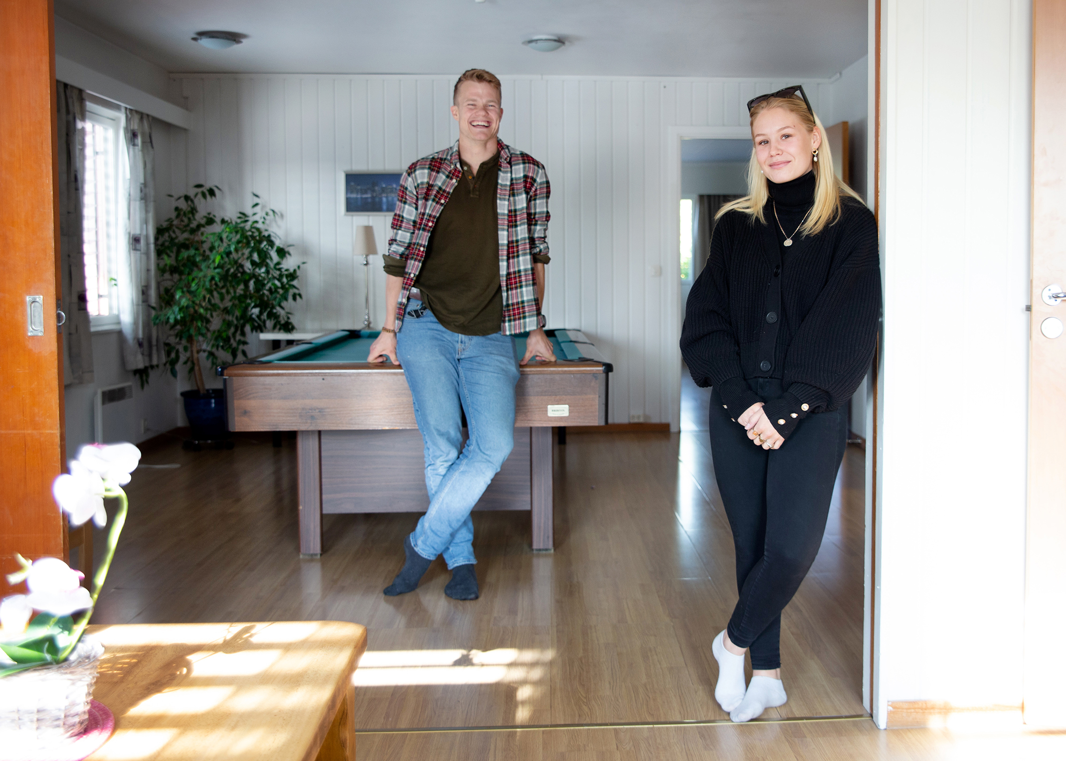 Bildet viser to personer innendørs. Siri står i fogrunnen og smiler, hun har på seg svart bukse og svart genser. Endre Kristensen står litt bak henne og lener seg på et biljardbord, han har olabukser og rutete skjorte.