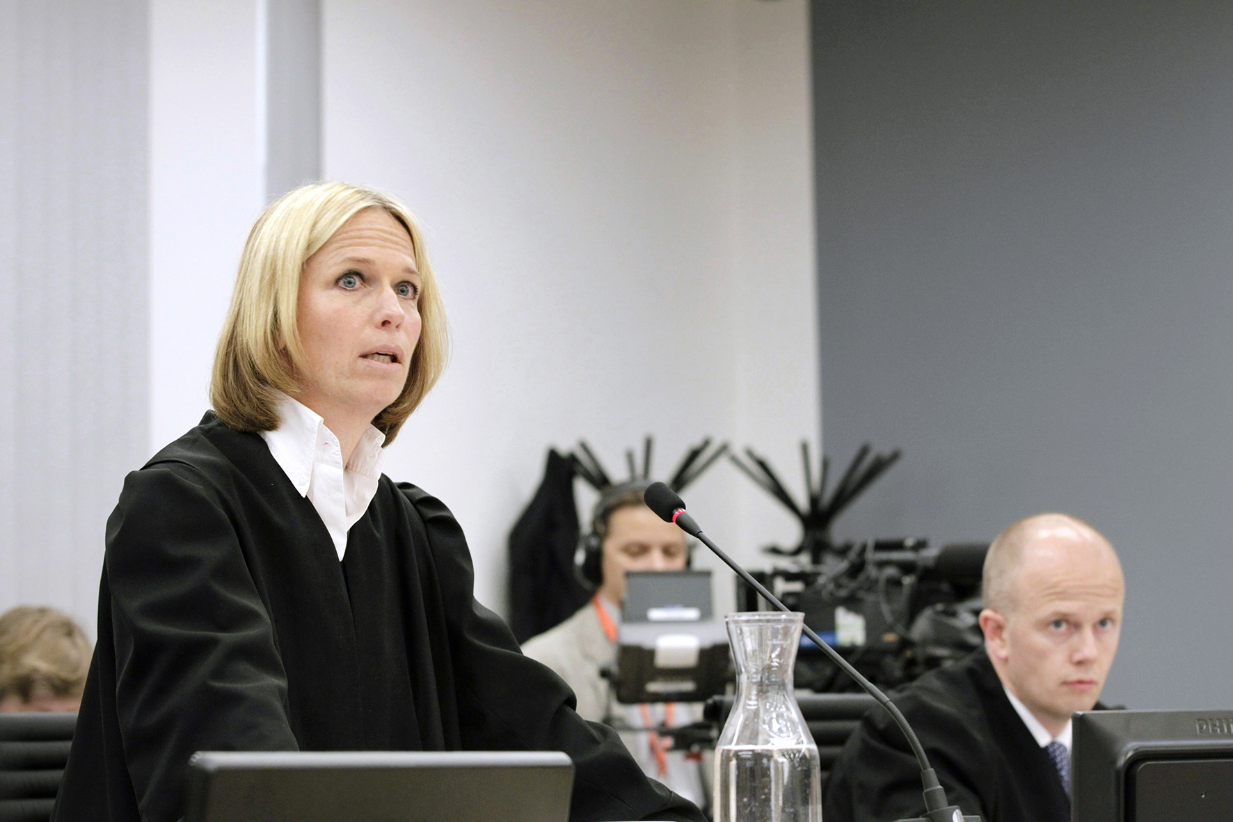 Inga Bejer Engh snakker i en mikrofon under rettsaken mot Anders Behring Breivik, Svein Holden sitter i bakgrunnen