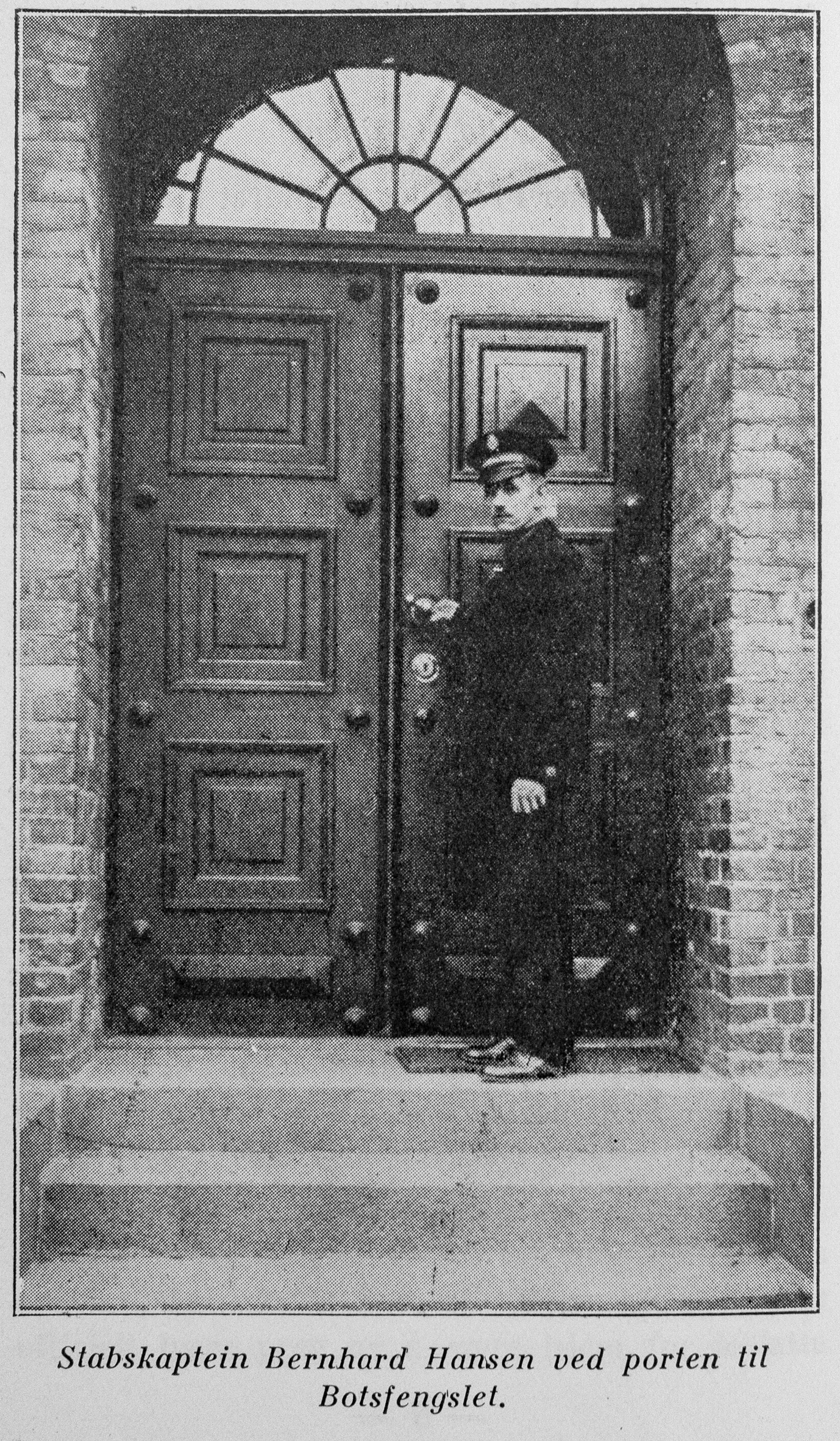 Bildet er et sort-hvitt arkivbilde som viser en mann i frelsesarmeens uniform som står utenfor døra inn til Botsfengselet og holder i dørhåndtaket.