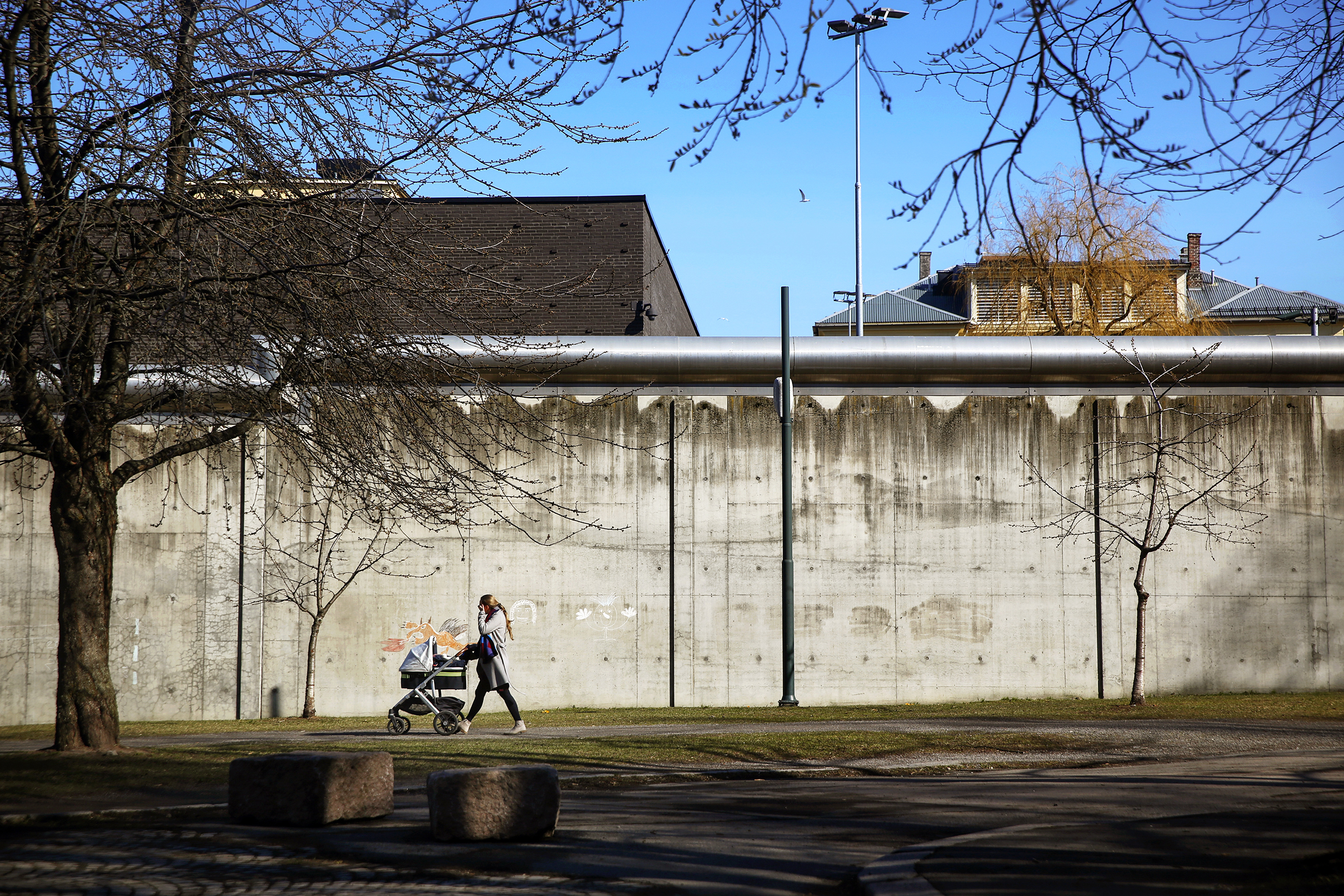 Bildet viser muren til Oslo fengsel. En kvinne med barnevogn er på vei forbi utenfor.