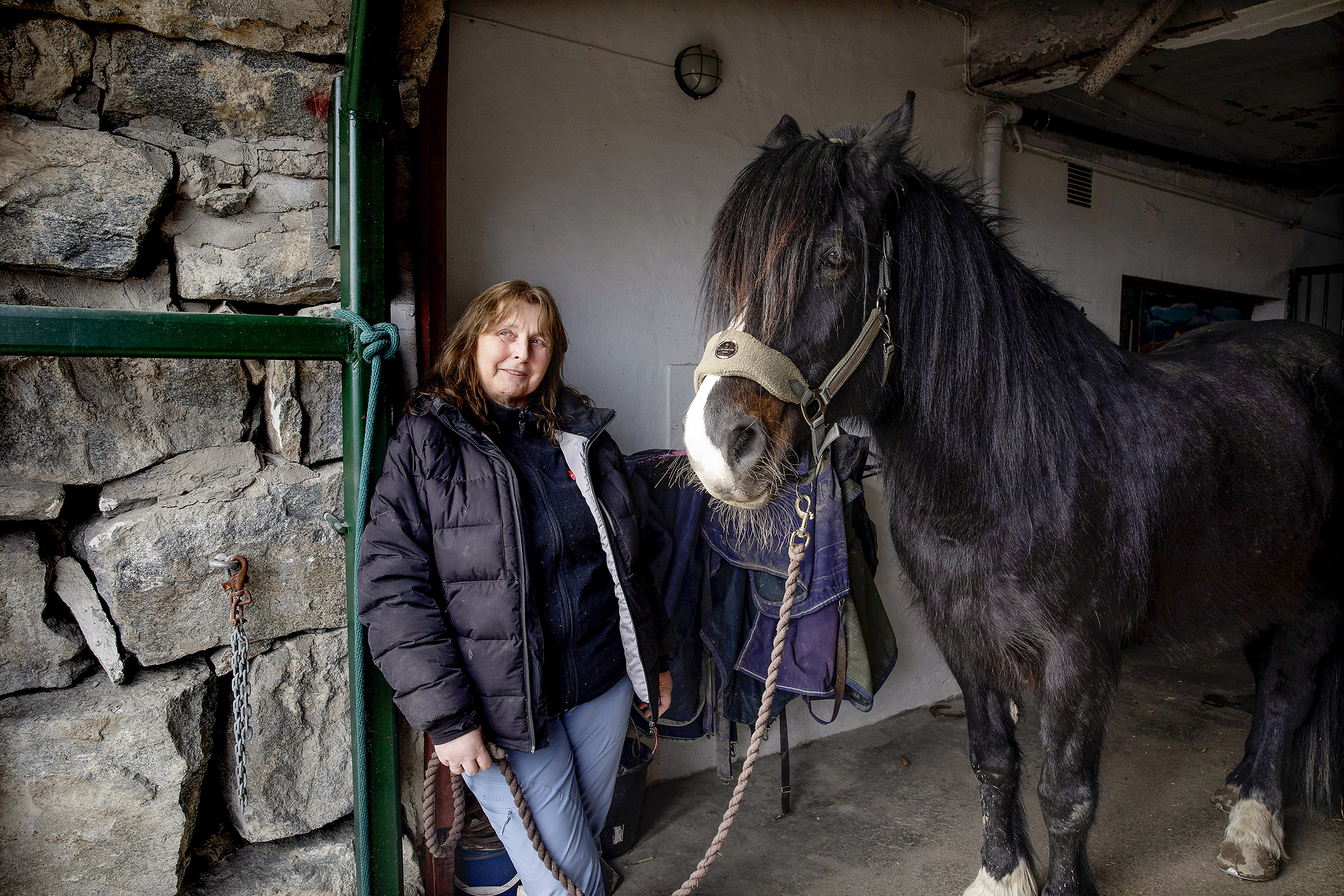 Nina Vartianen er ansatt på behandlingstunet, her står hun i stallen med en av hestene