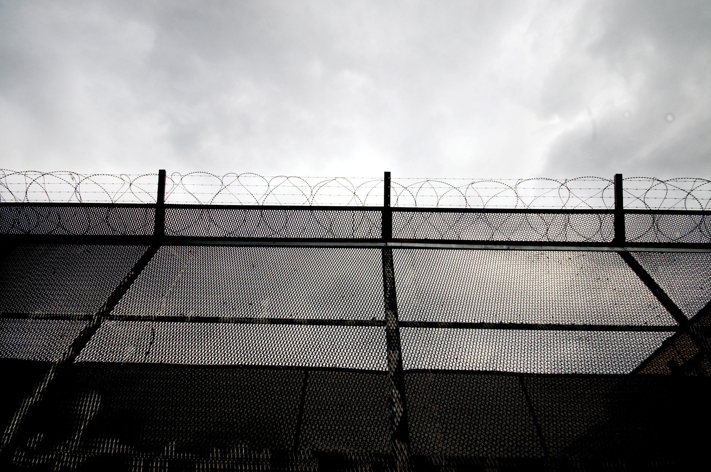 Bilde tatt oppover fengselmurer og høye gjerder.