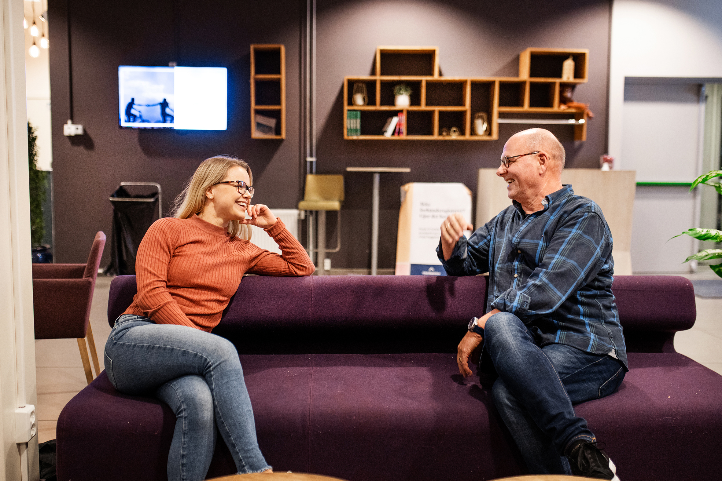 Bildet viser Lisa og Egil som sitter på en lilla sofa, ser på hverandre og smiler