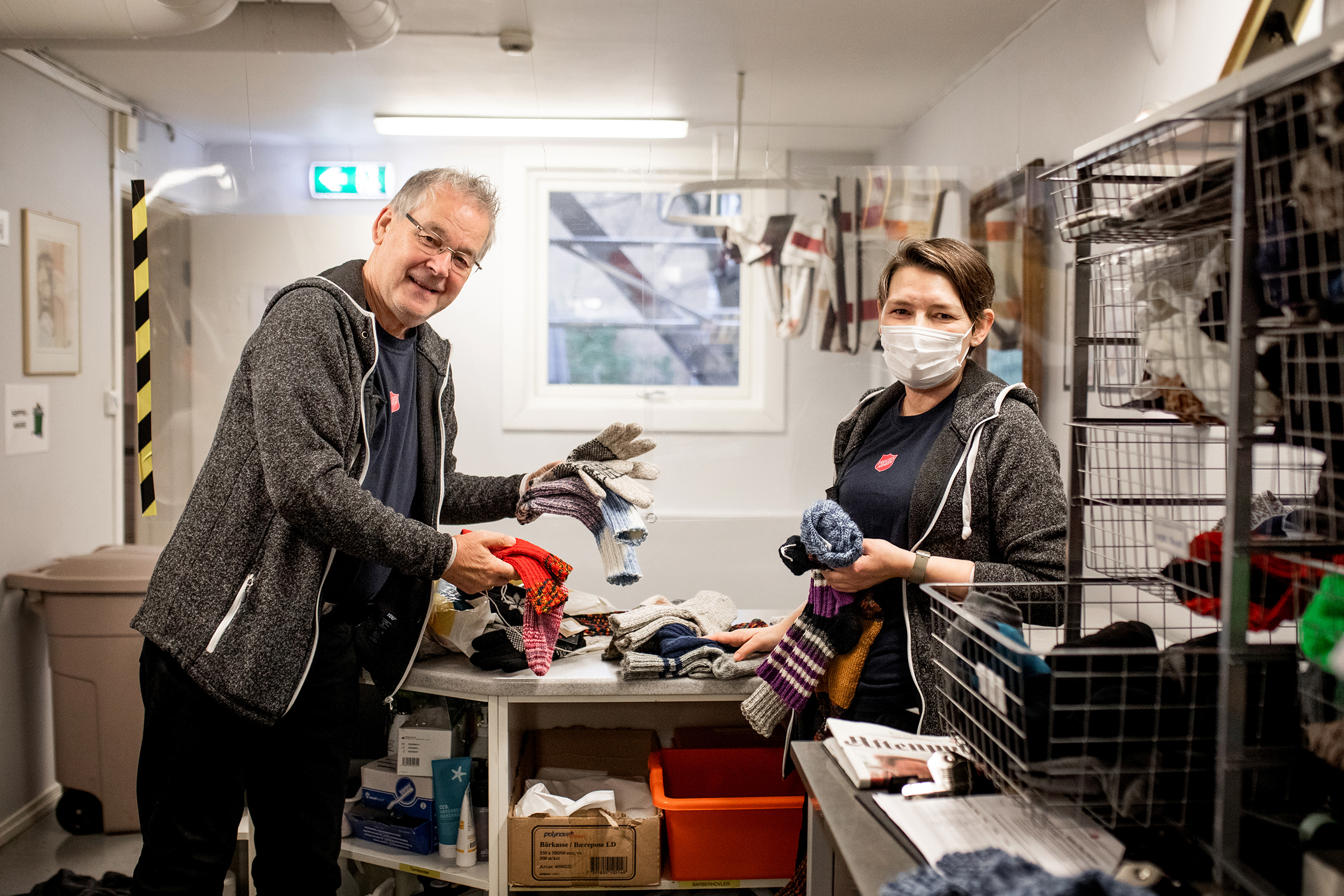 Oberstløytnant Odd Berg leverer en haug med strikkede sokker til Jeanette på klesutdelingen på Fyrlyset.