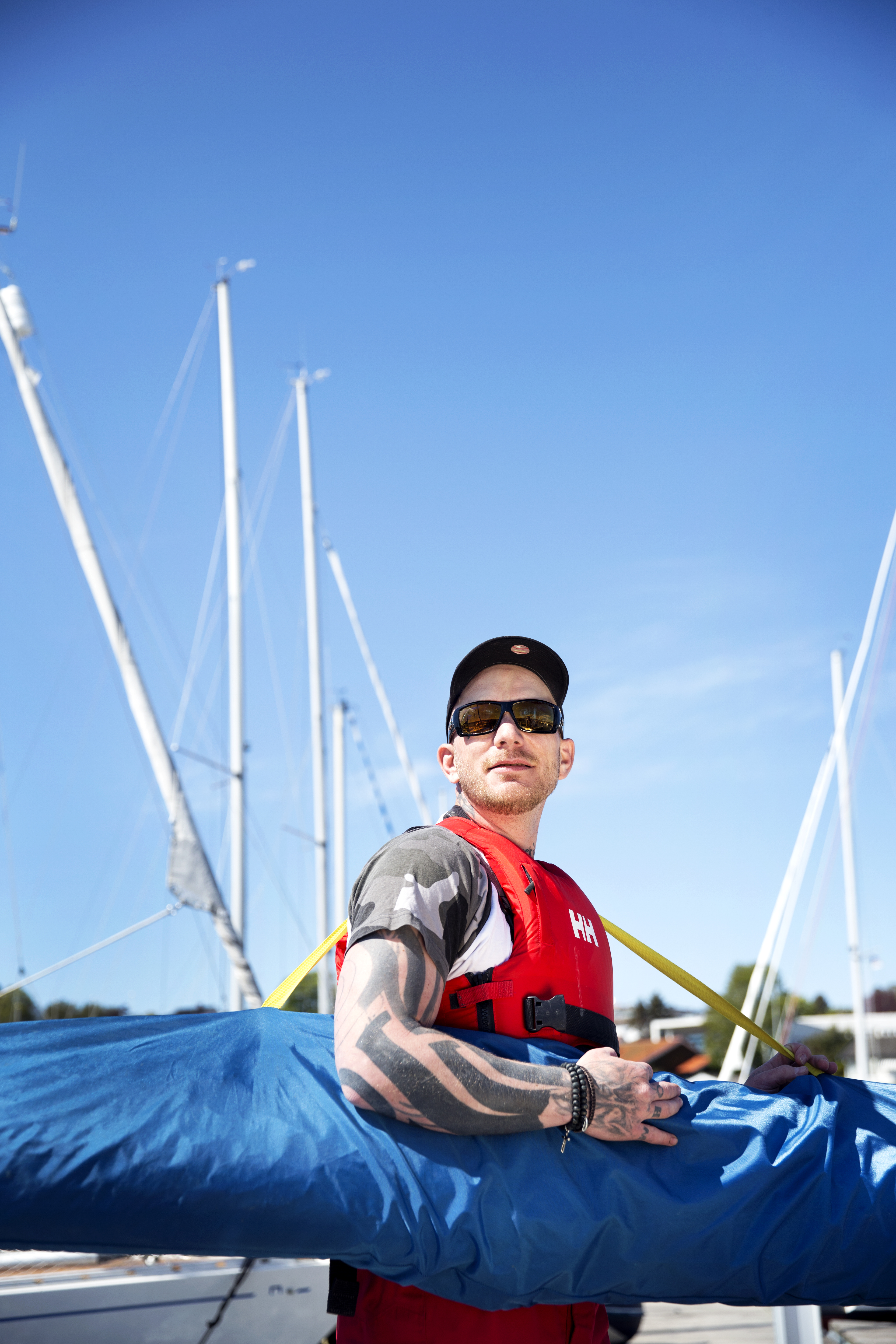 En av deltakerne på Frisk seilas står med caps, solbriller og flytevest.