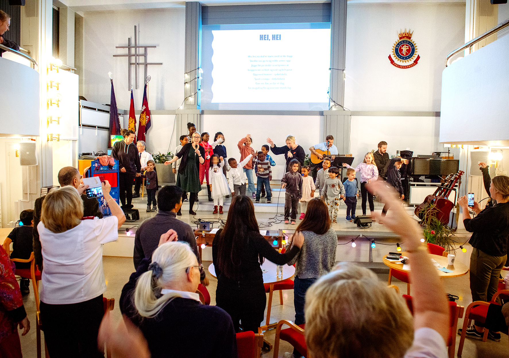 På Frelsesarmeen på Grønland er det et yrende mangfold av aldersgrupper og nasjonaliteter. Her er det mangebarn som synger sammen på scenen, mens foreldre og voksne er engasjert publikum.