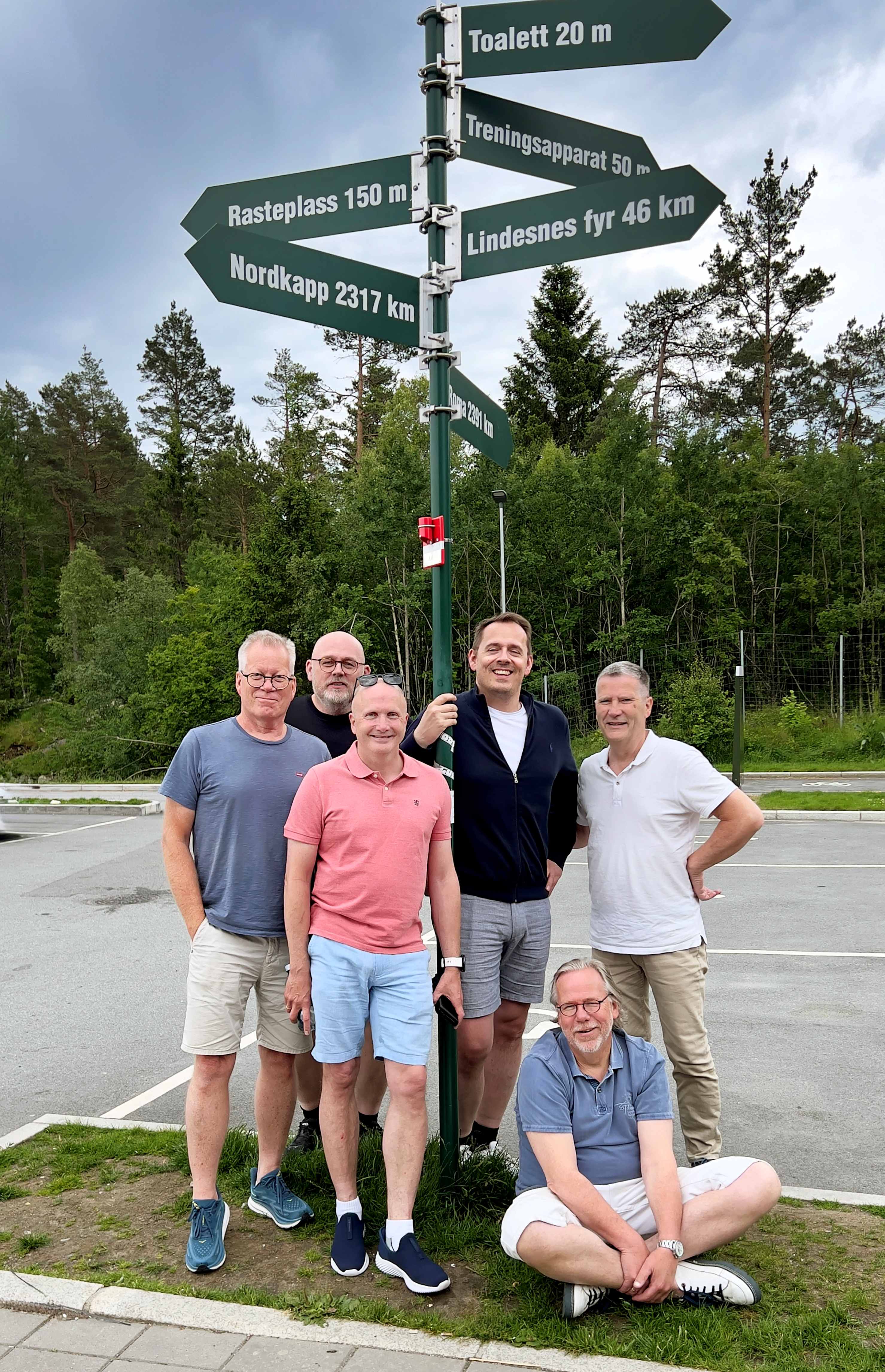 Medlemmene i fritidstøy ved et veiskilt utendørs