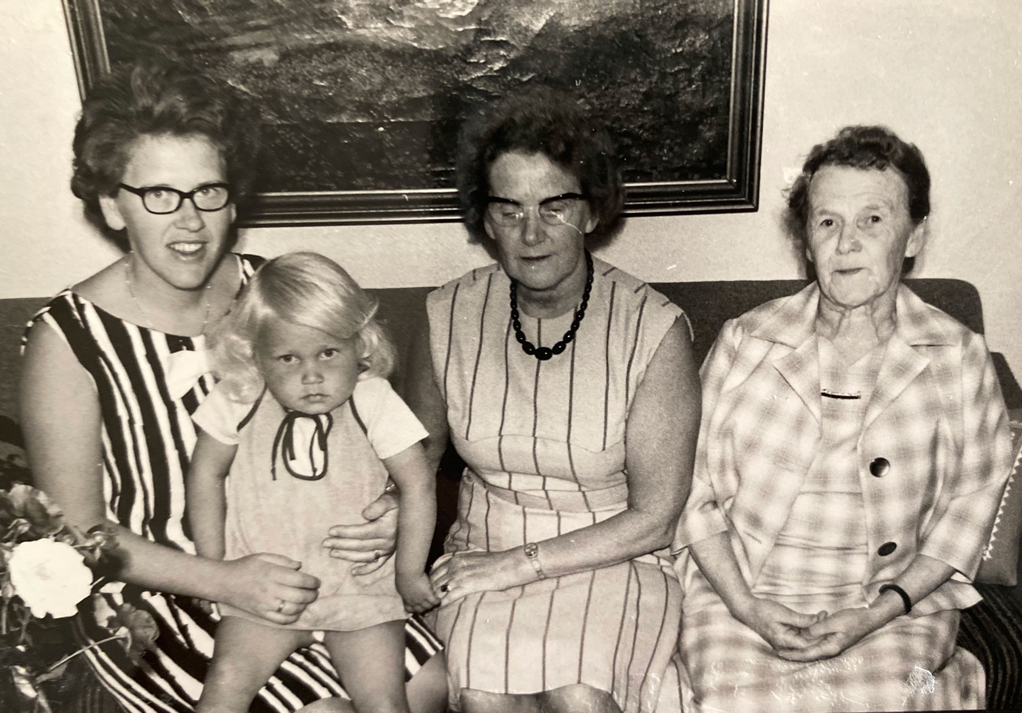 Bilde fra 1960-tallet i svart hvitt med liten jente på fang og en kvinne i 20-årene, en i 50-årene og en i 70-årene.
