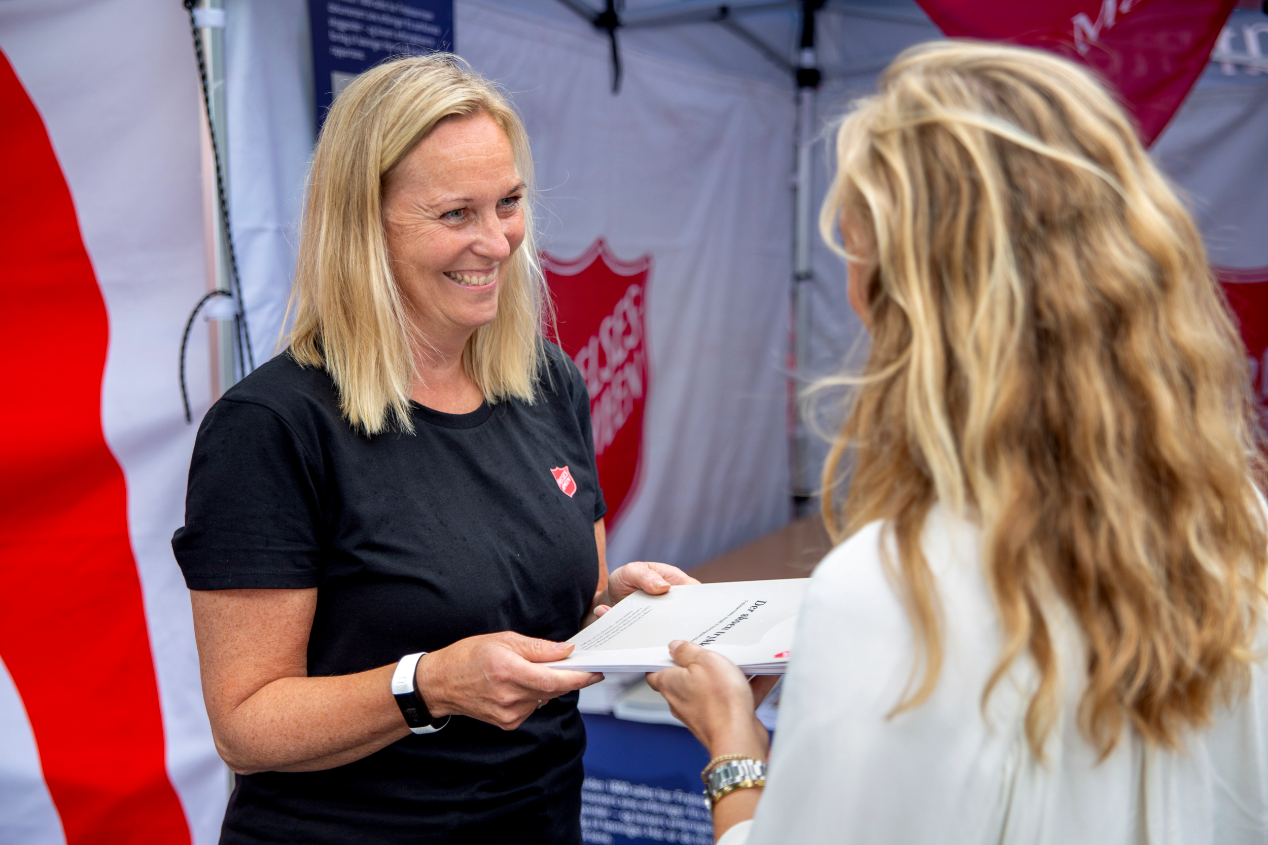 Foto: Blond kvinne deler ut rapport til en annen kvinne.