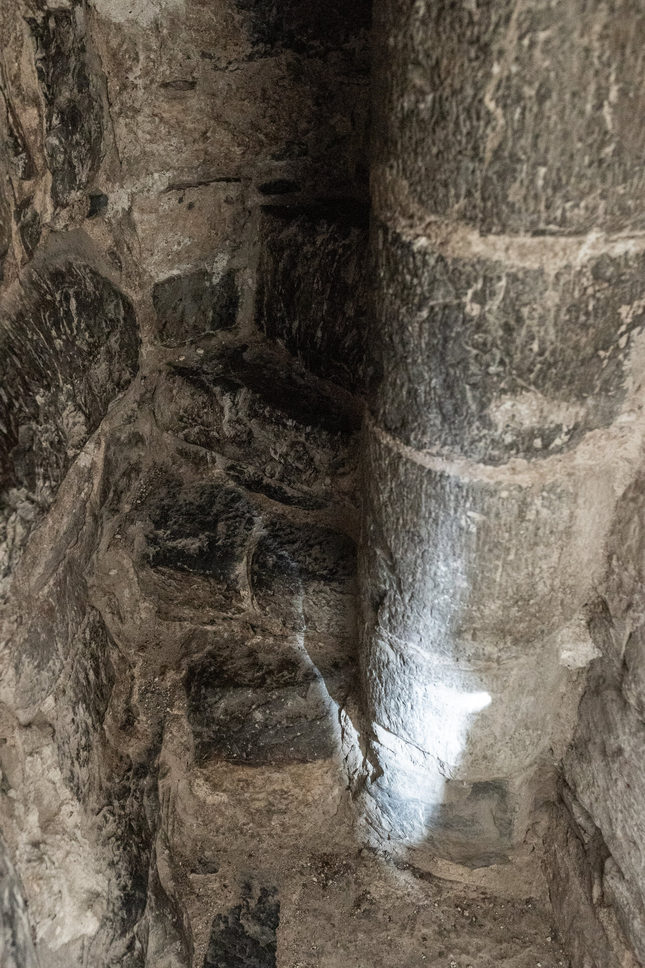Foto: tre gamle, smale trappetrinn i stein, resten av trappen forsvinner inn i muren.