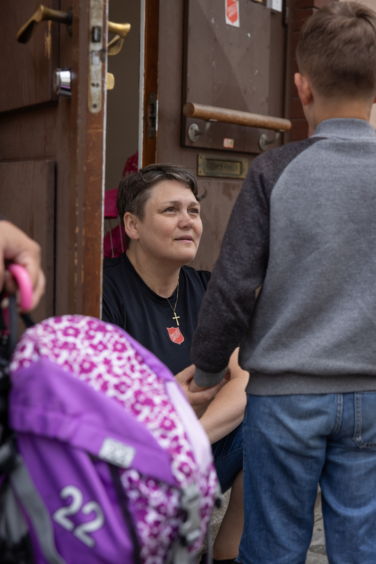 Korpsleder Siv Joensen i Drammen sitter på huk i døråpningen og snakker med et barn.