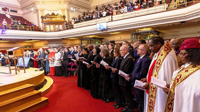 Representanter fra diplomati, kirkeliv, samfunnsliv og akademia sammen med General Lyndon Buckingham, kommandør Bronwyn Buckingham, kommandør Jane Paone og oberstløytnant Nick Coke som representerte Frelsesarmeen. Stående i kirken under felles salmesang