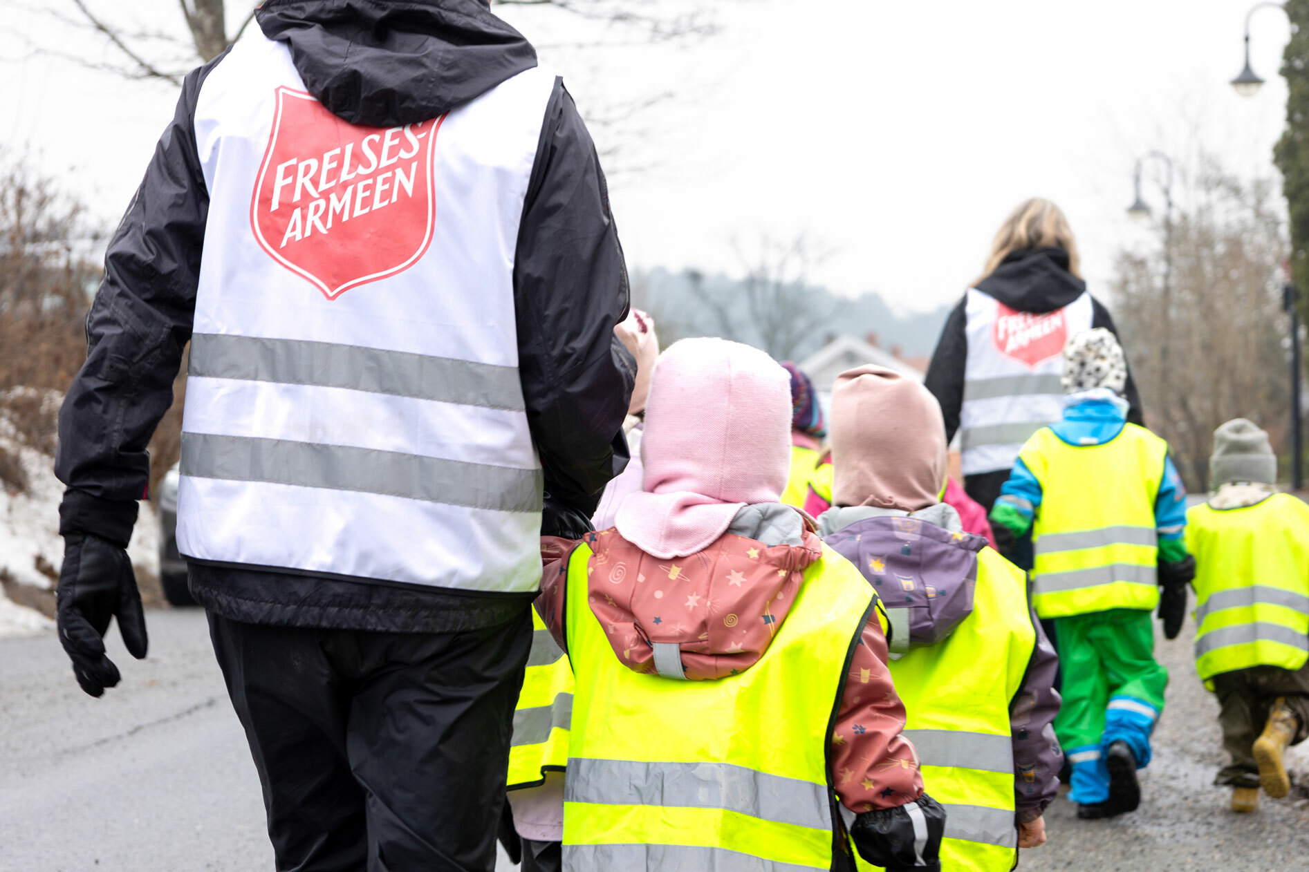 Foto: To bildere etter hverandre der det første viser en gjeng med barnehagebarn og to ledere som går langs en vei. De har på seg refleksvester. Det andre bildet viser dem leke i de samme vestene på en sandstarnd ved sjøen.