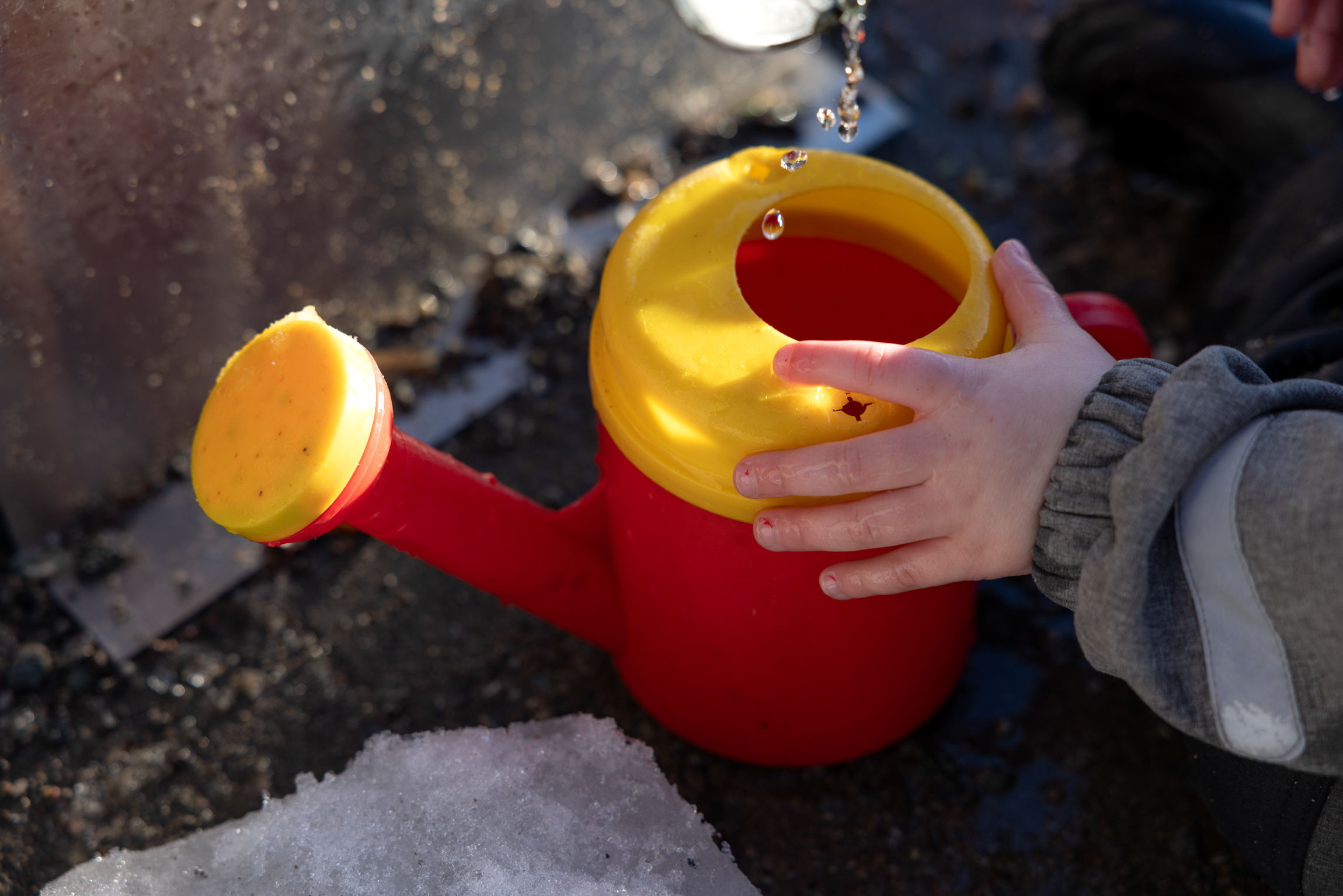 To bilder som begge viser barnehender som leker i sandkassen