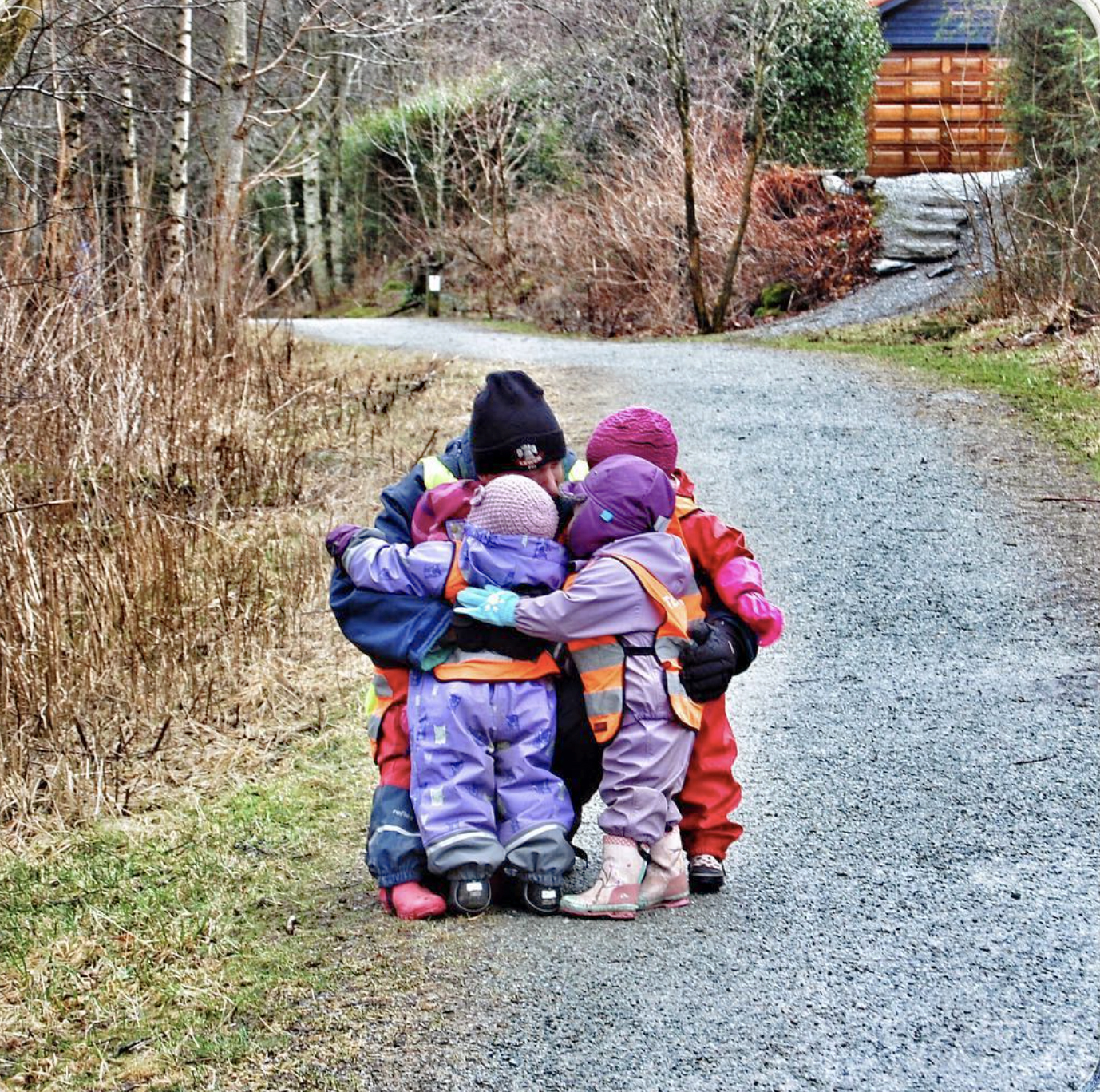 Foto: Voksen person på tur med fire barn på en sti. De tar en gruppeklem.