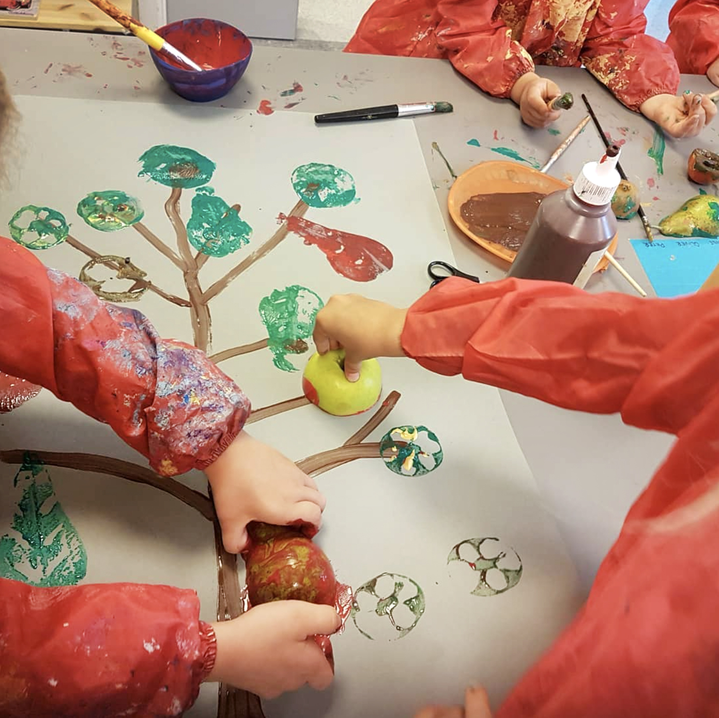 Foto: To bilder etter hverandre. På det første bruker barn epler til å trykke med maling på et stort papir. De lager et tre. På det andre er det barn som leker ved et bord.