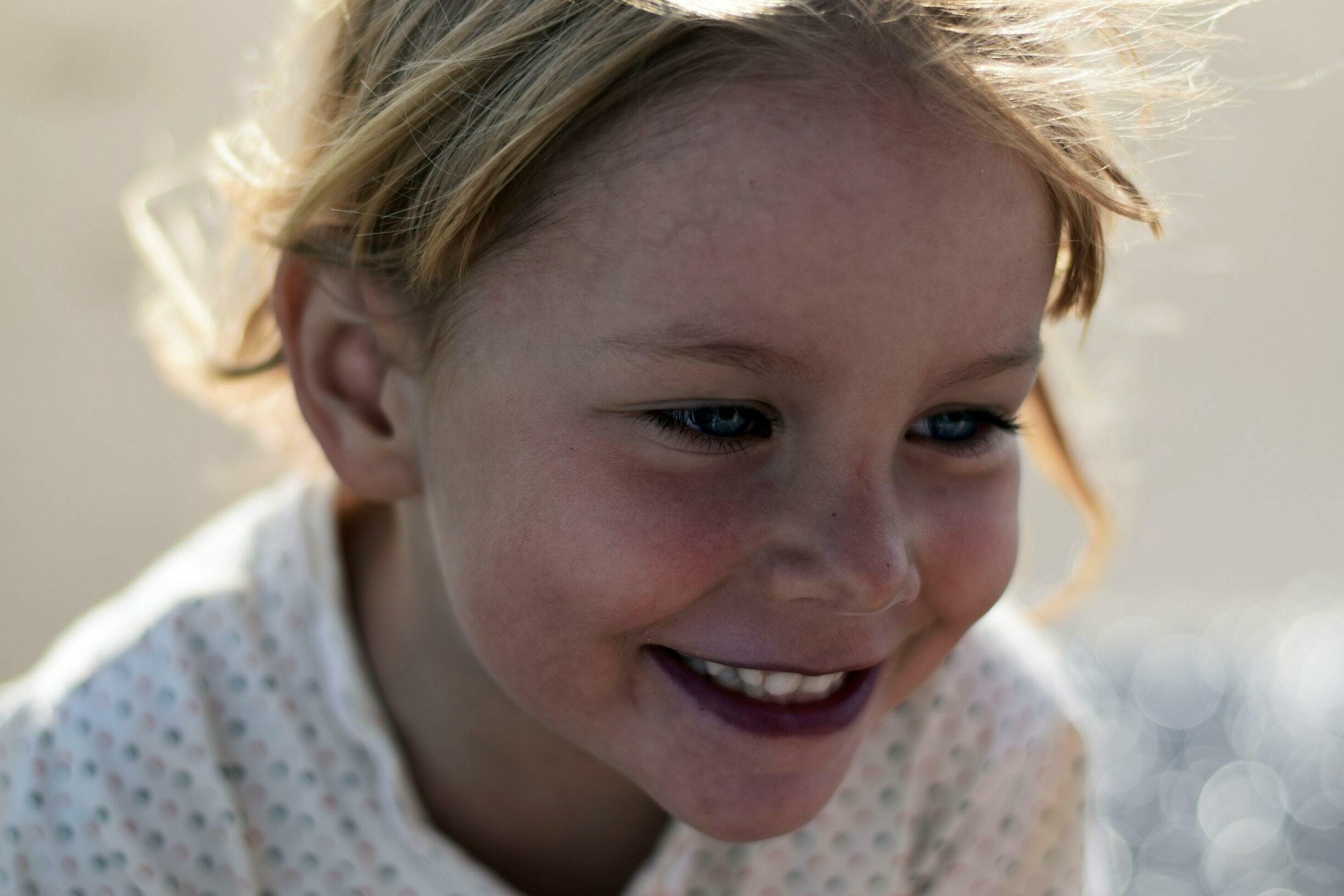 Foto: Nærbilde av ansiktet til en smilende jente på rundt 6 år.