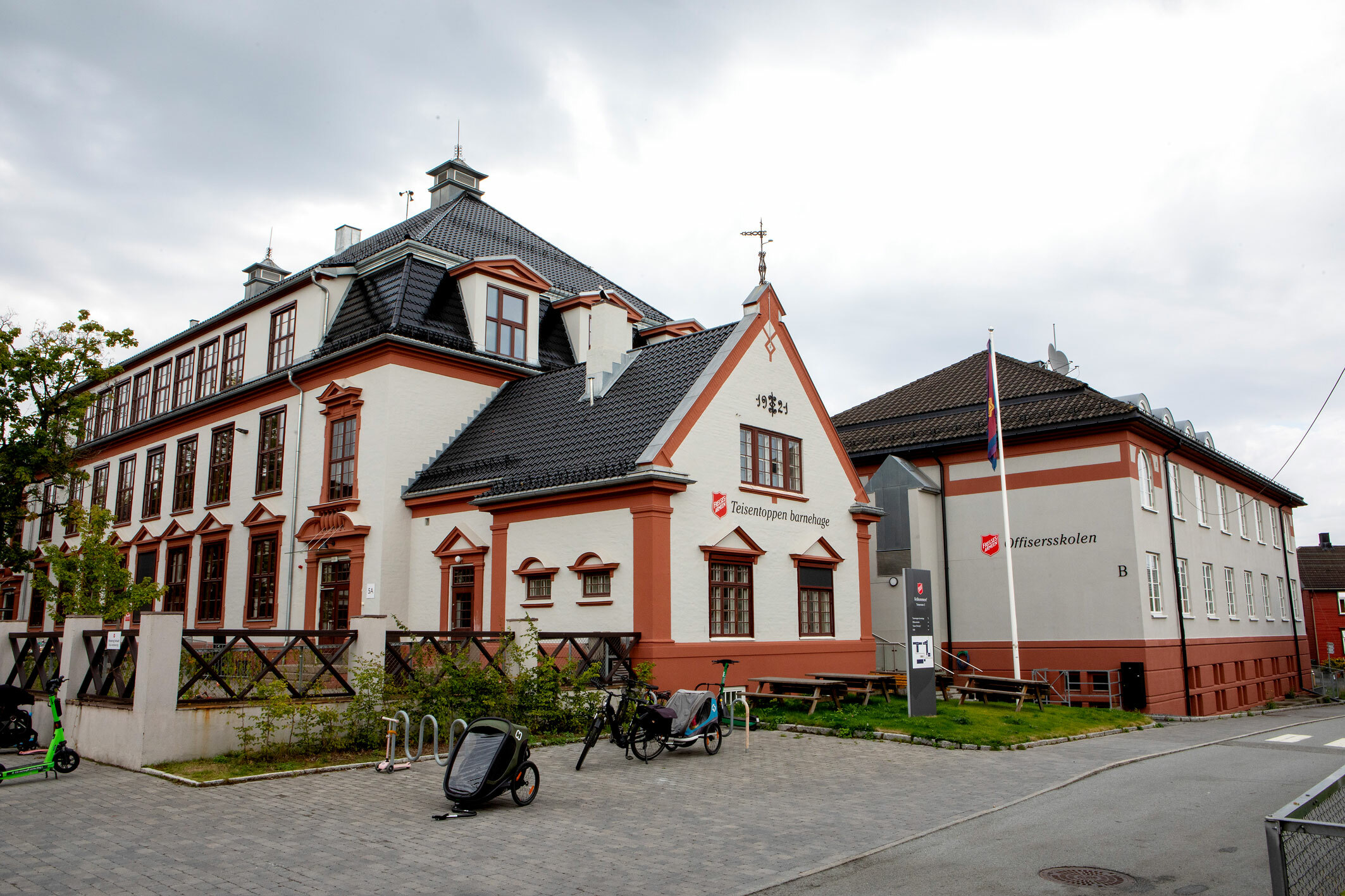 Foto: Eksteriør av stort, gammelt murbygg malt i beige og lakeserødt.