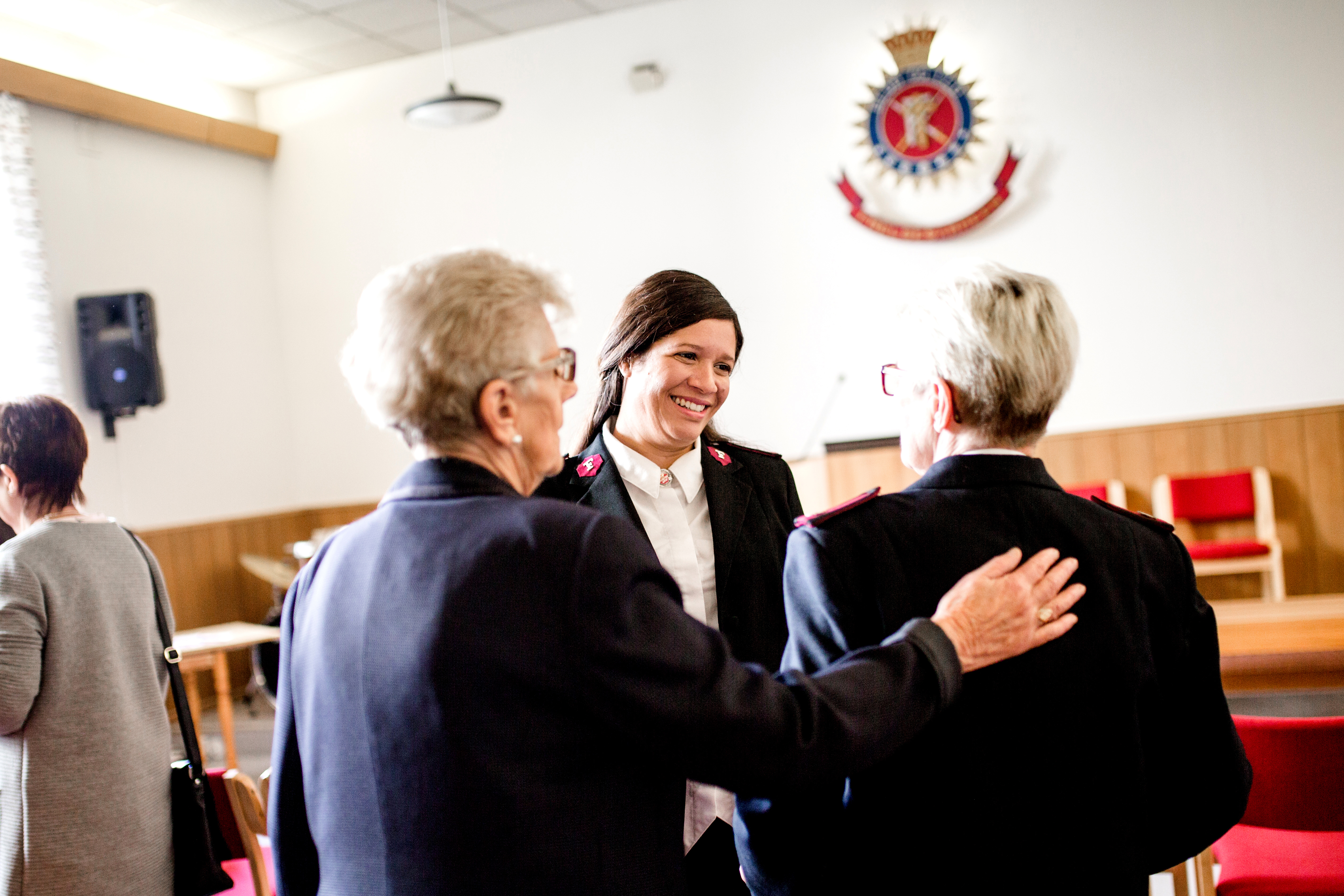 Damer i møtelokale i Frelsesarméuniform, smilende