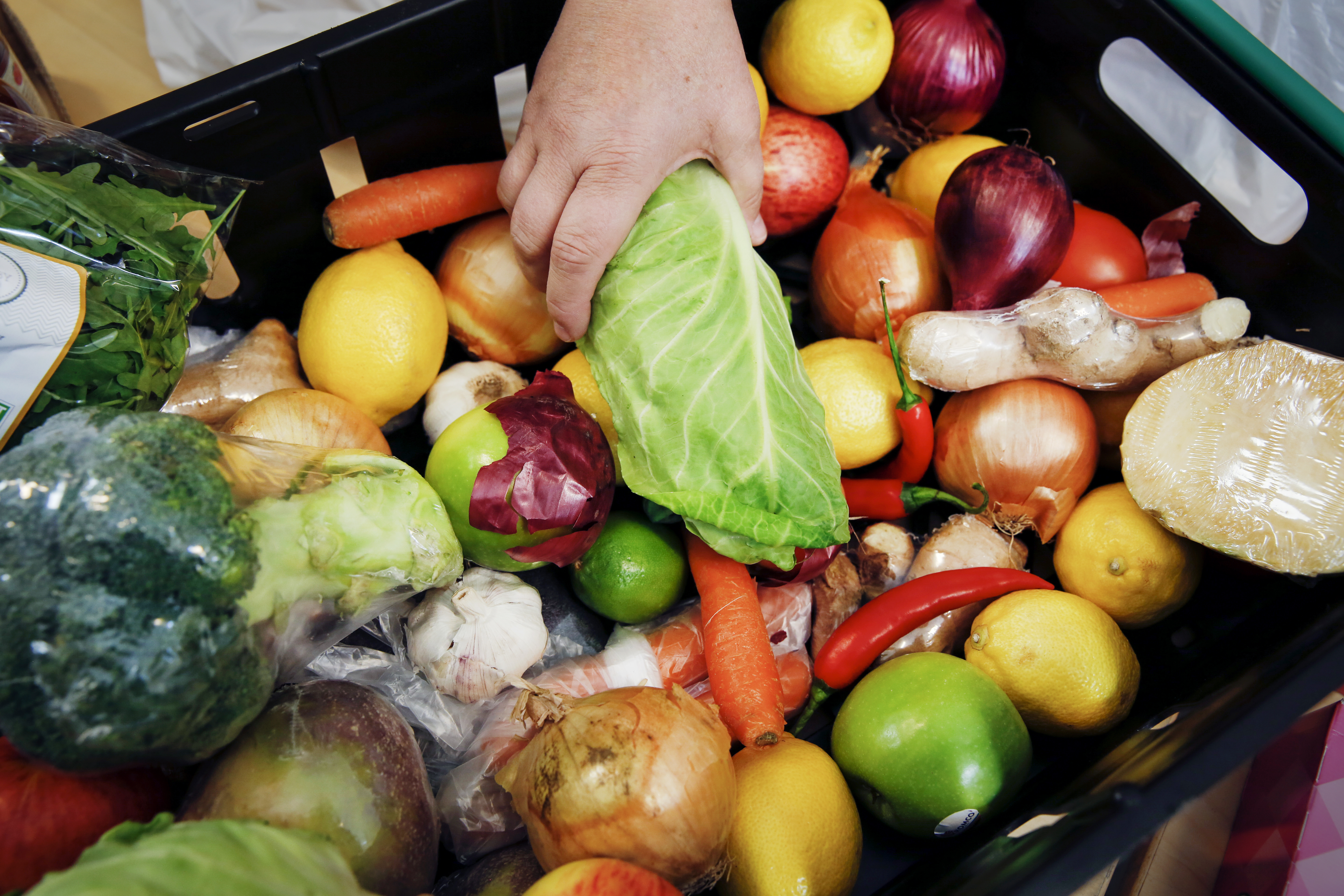 Kasse med grønnsaker, en hånd holder i en salat