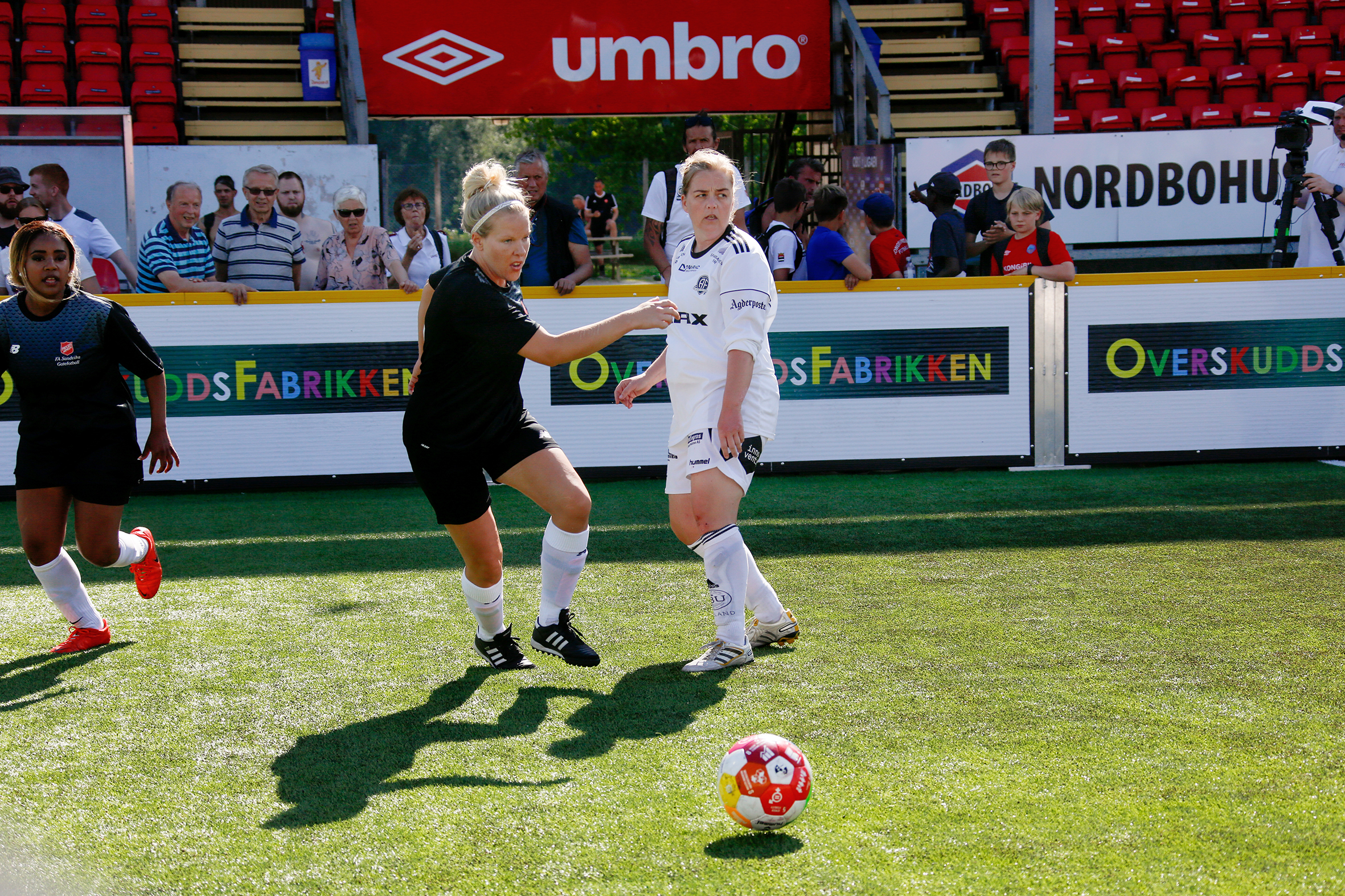 Cathrine Johansen er på fotballbanen i kampsituasjon for gatefotballen i Sandvika under NM i gatefotball på Kongsvinger i 2018. Hu tar sats for skudd. Det er to andre spillere i  bildet også, en av dem Sandvika-spiller, den andre fra et motstanderlag.