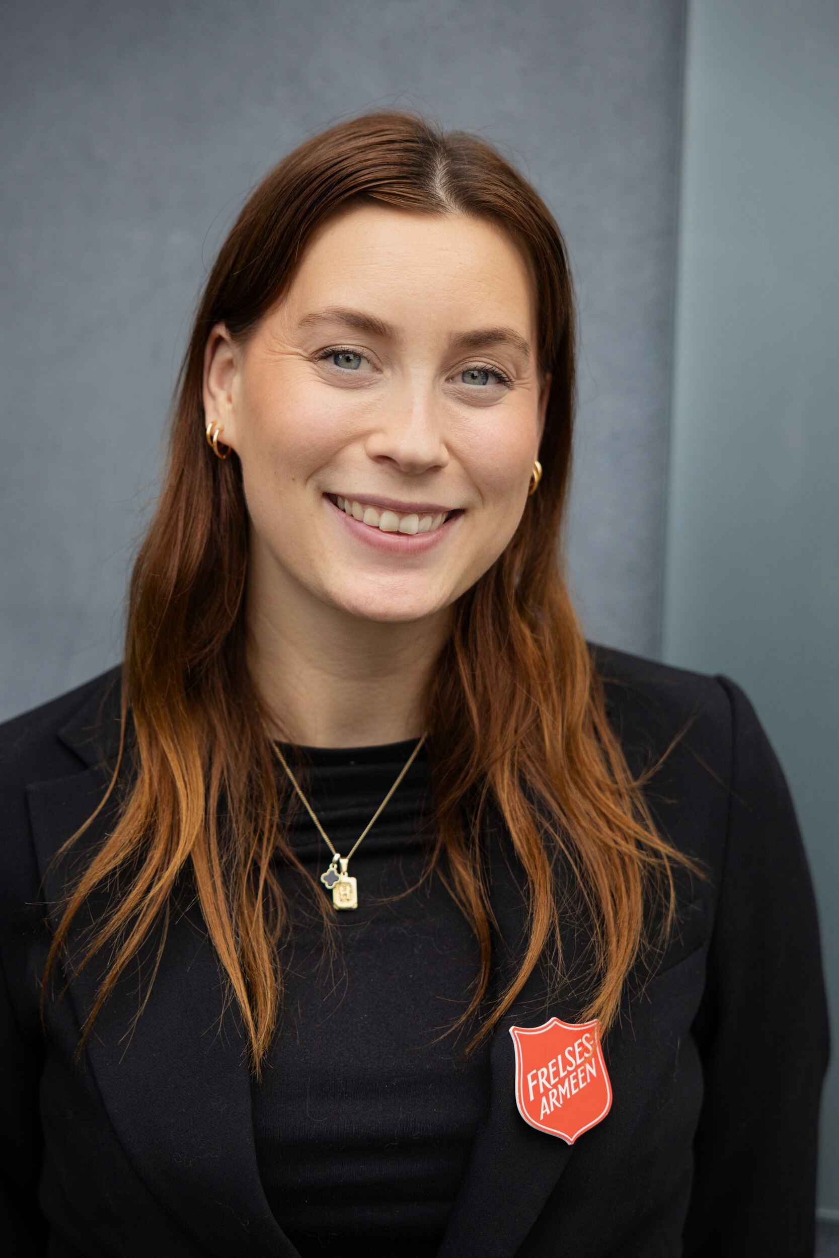 Portrett Silje Aastrøm i mørk jakke med Frelsesarmeens skjold på jakkeslaget.