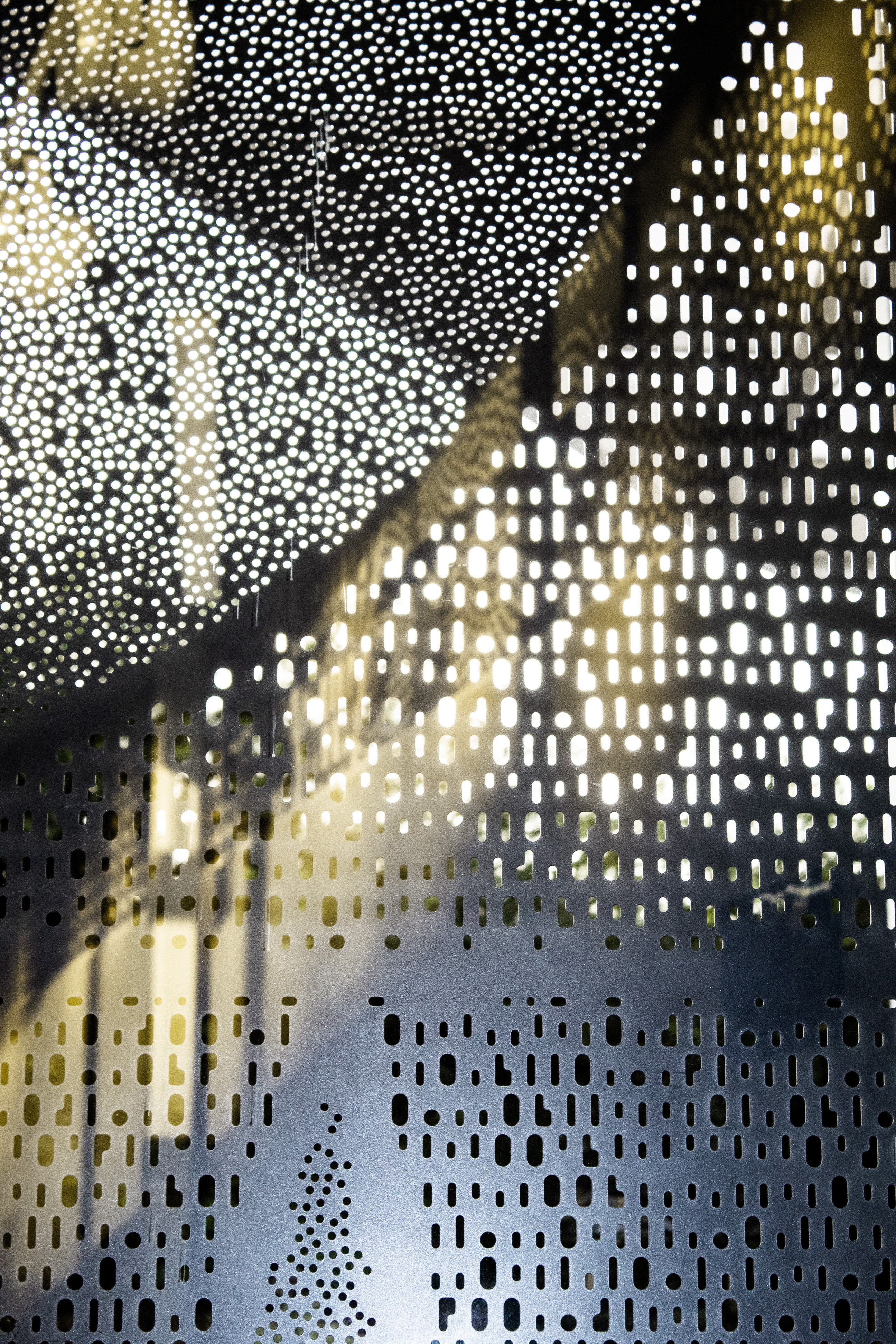 Textural close-up of a window with natural light filtering through organically shaped holes.
