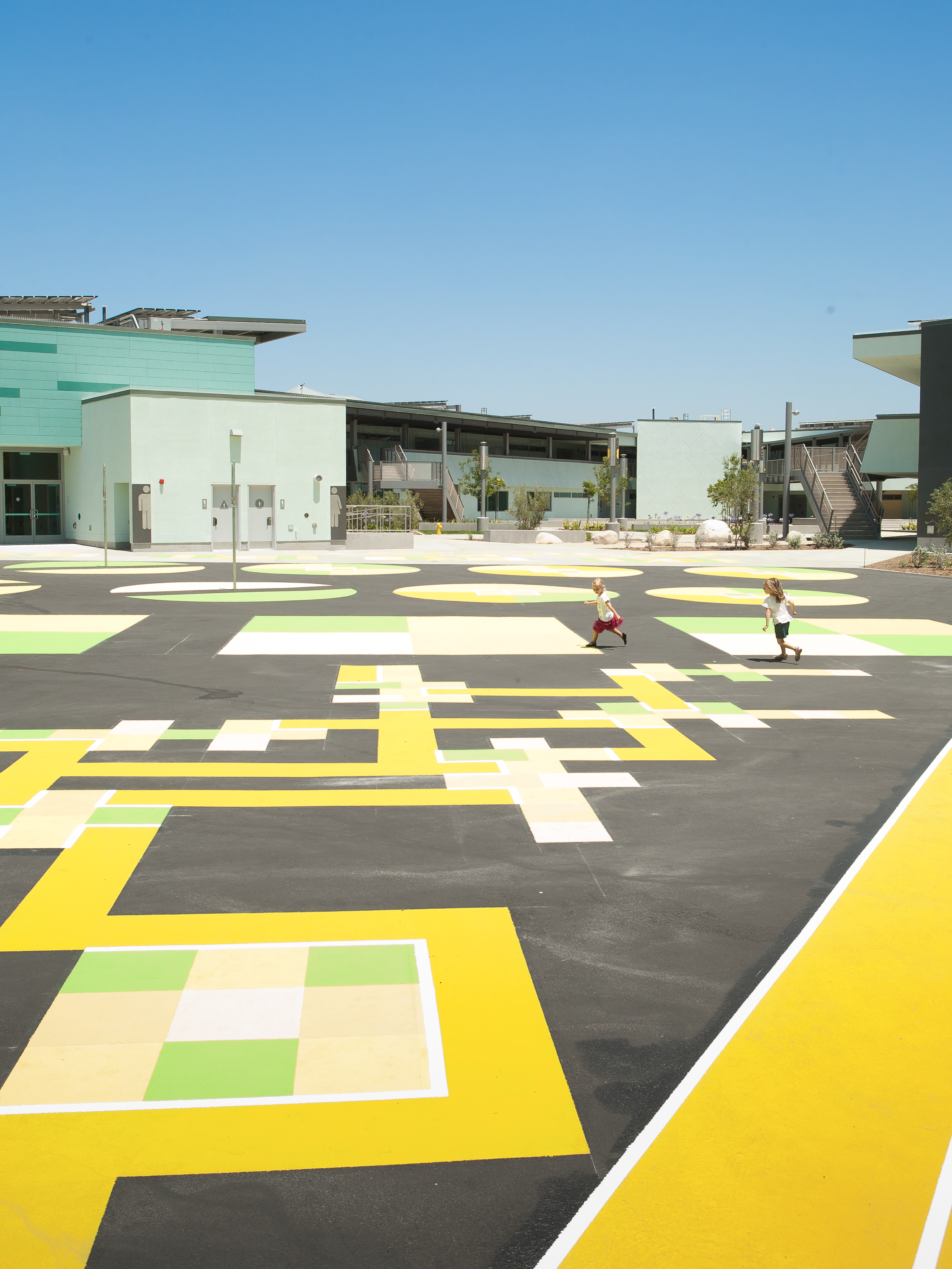 Photo of the campus exterior with graphic shapes on the floor, and students running.