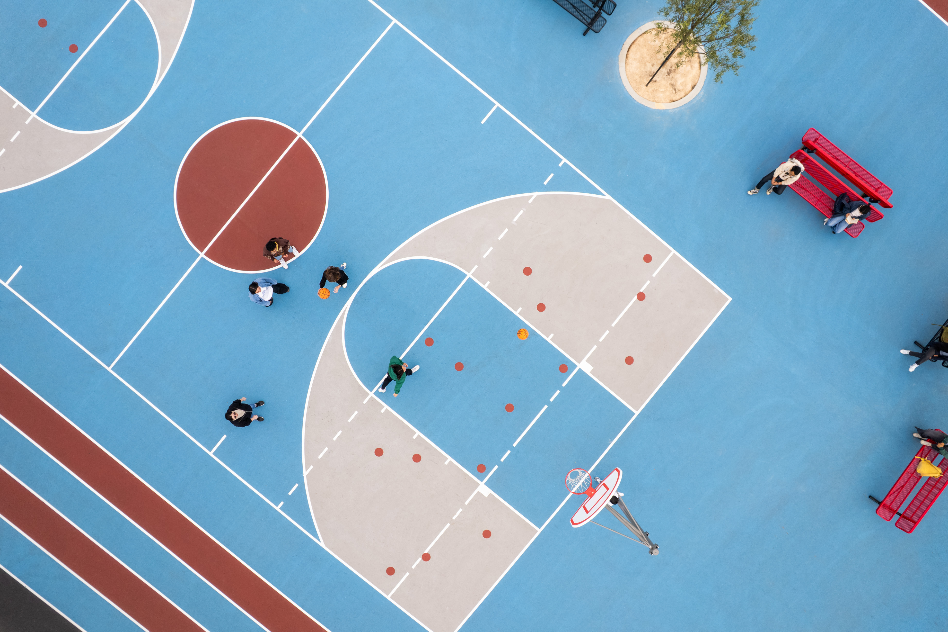Aerial shot of a basketball court in red, blue, and off-white color palette.