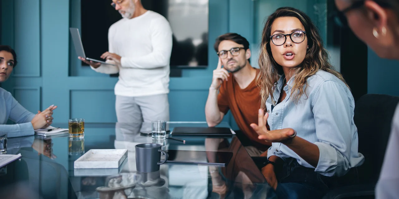 Faites carrières chez COFOMO en transformation numérique et intelligence artificielle - Femme discutant avec des clients autour d'une table.