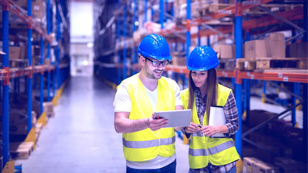 Two people in a distribution warehouse consulting an iPad using a ServiceNow solution.
