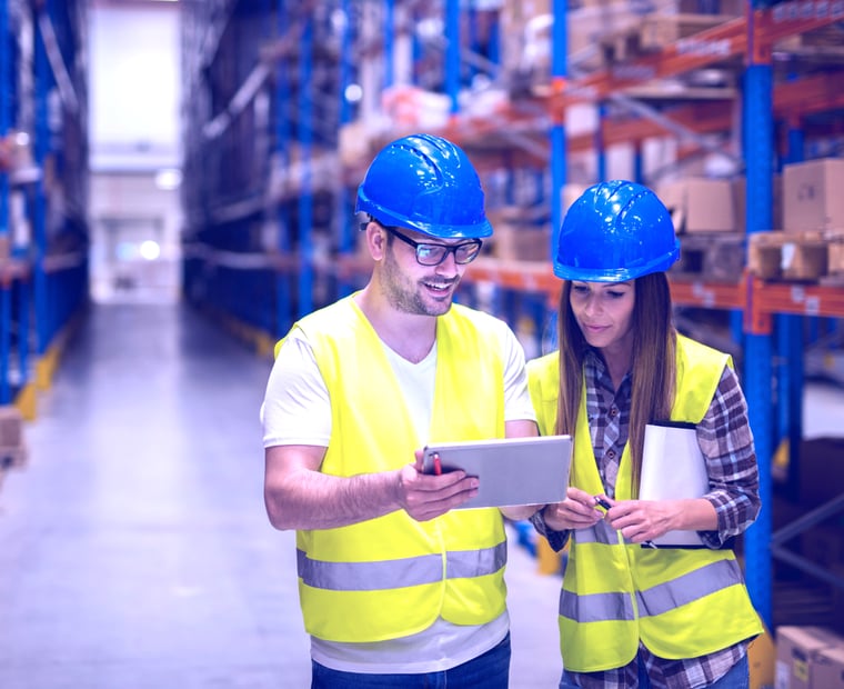 Deux personnes dans un entrepôt de distribution consultant un ipad grâce à une solution ServiceNow.