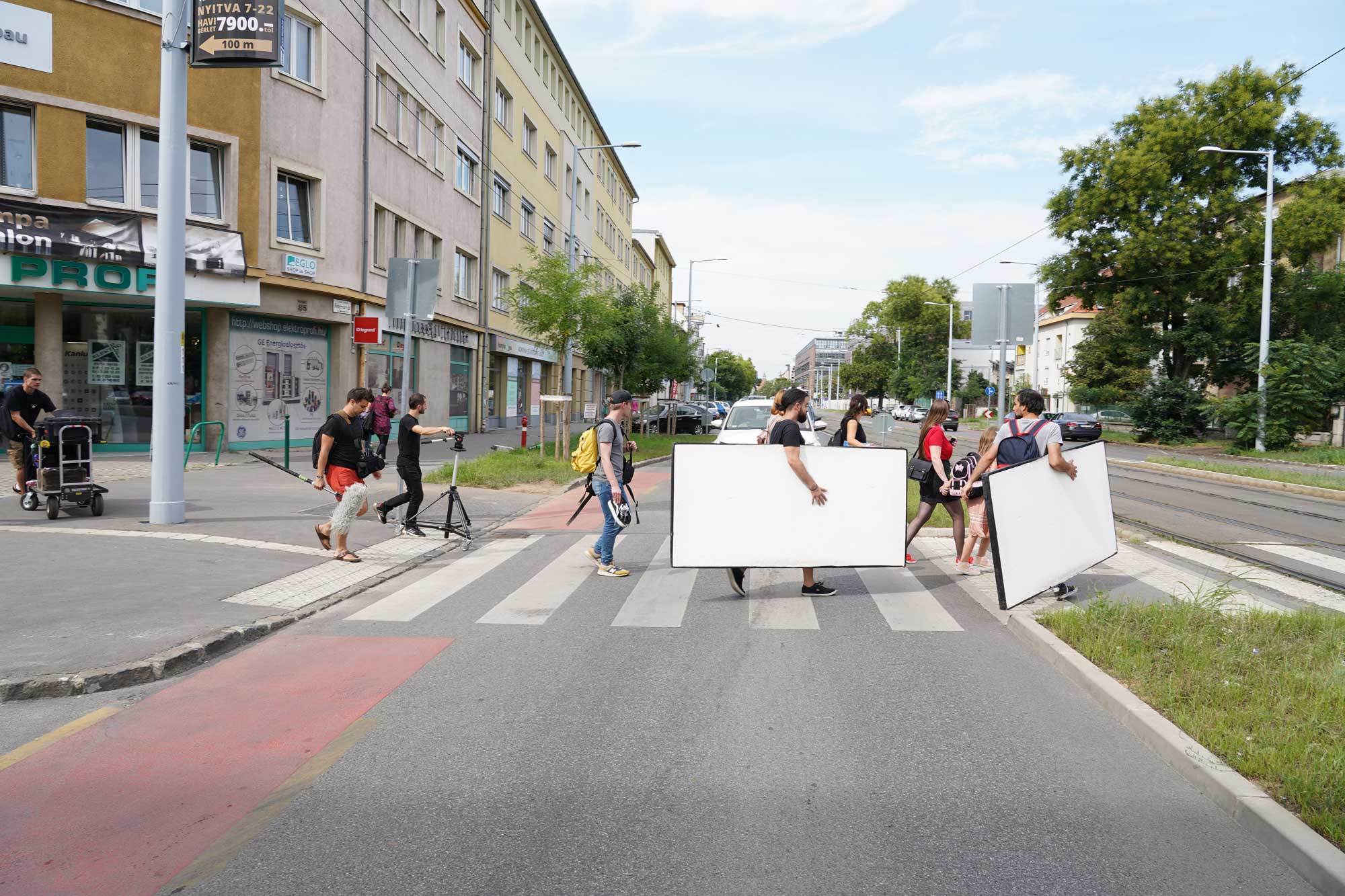 Students carrying filming equipment across a road in Hungary